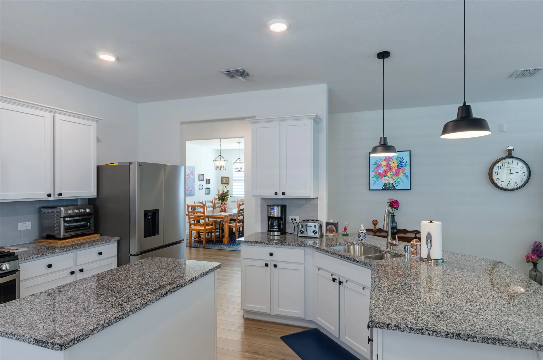 Kitchen with granite countertops, white cabinetry, stainless steel refrigerator, recessed lighting, and wood-finish flooring