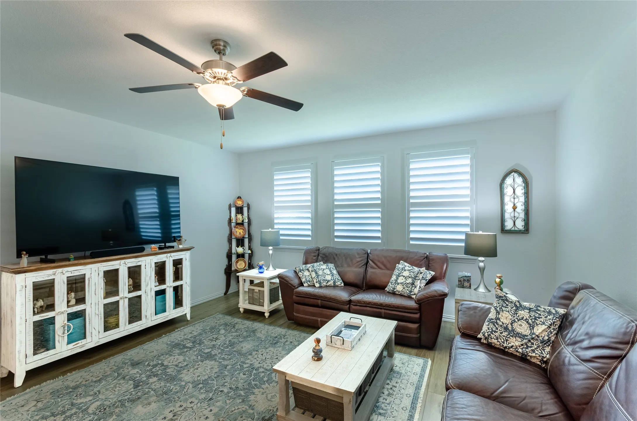 Bedoom or office featuring a ceiling fan with integrated lighting, an arched window with plantation shutters, and light-colored carpeting