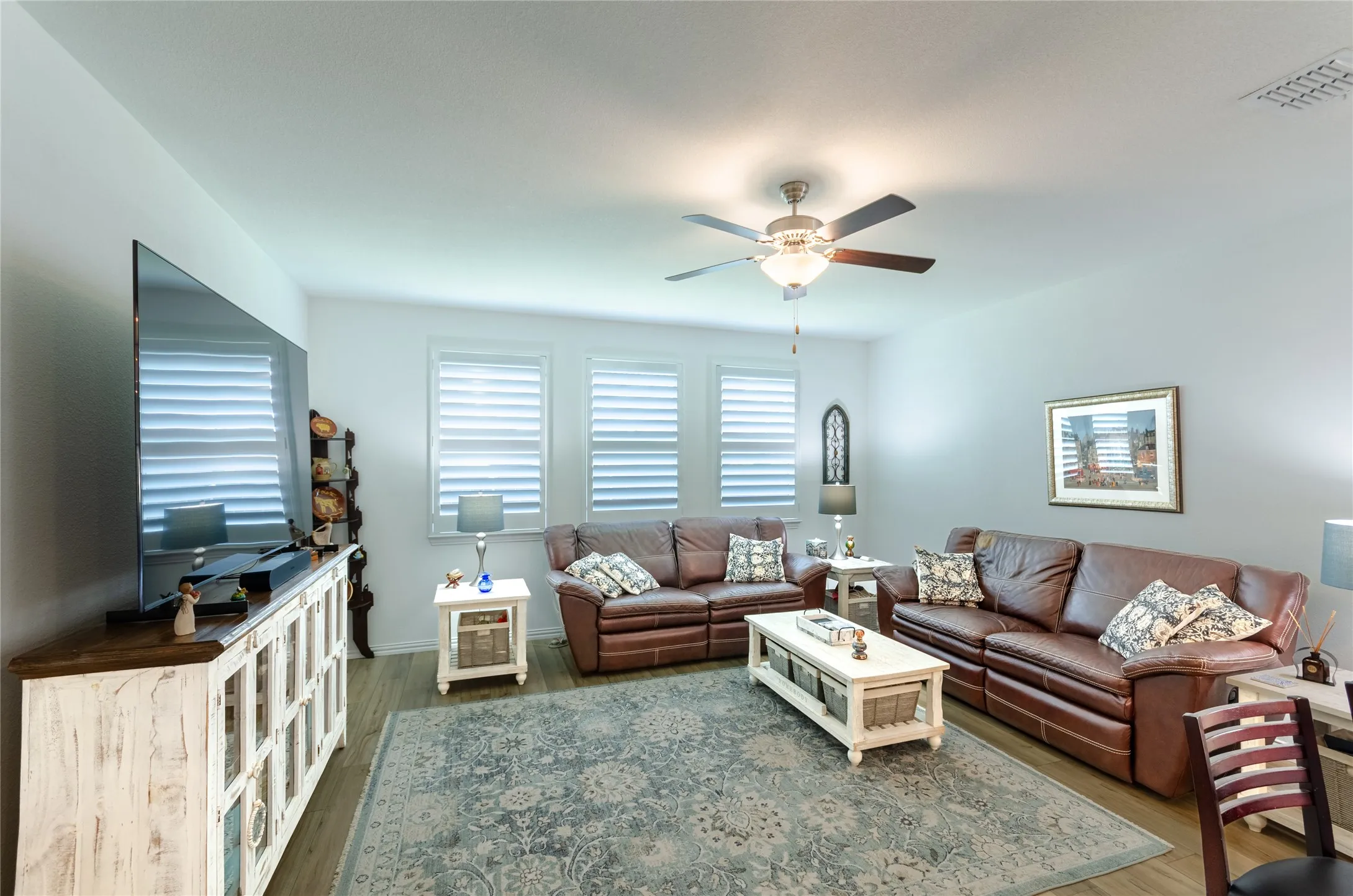 Recessed lighting, ceiling fan, wood-finish flooring, multiple windows, and a built-in media console