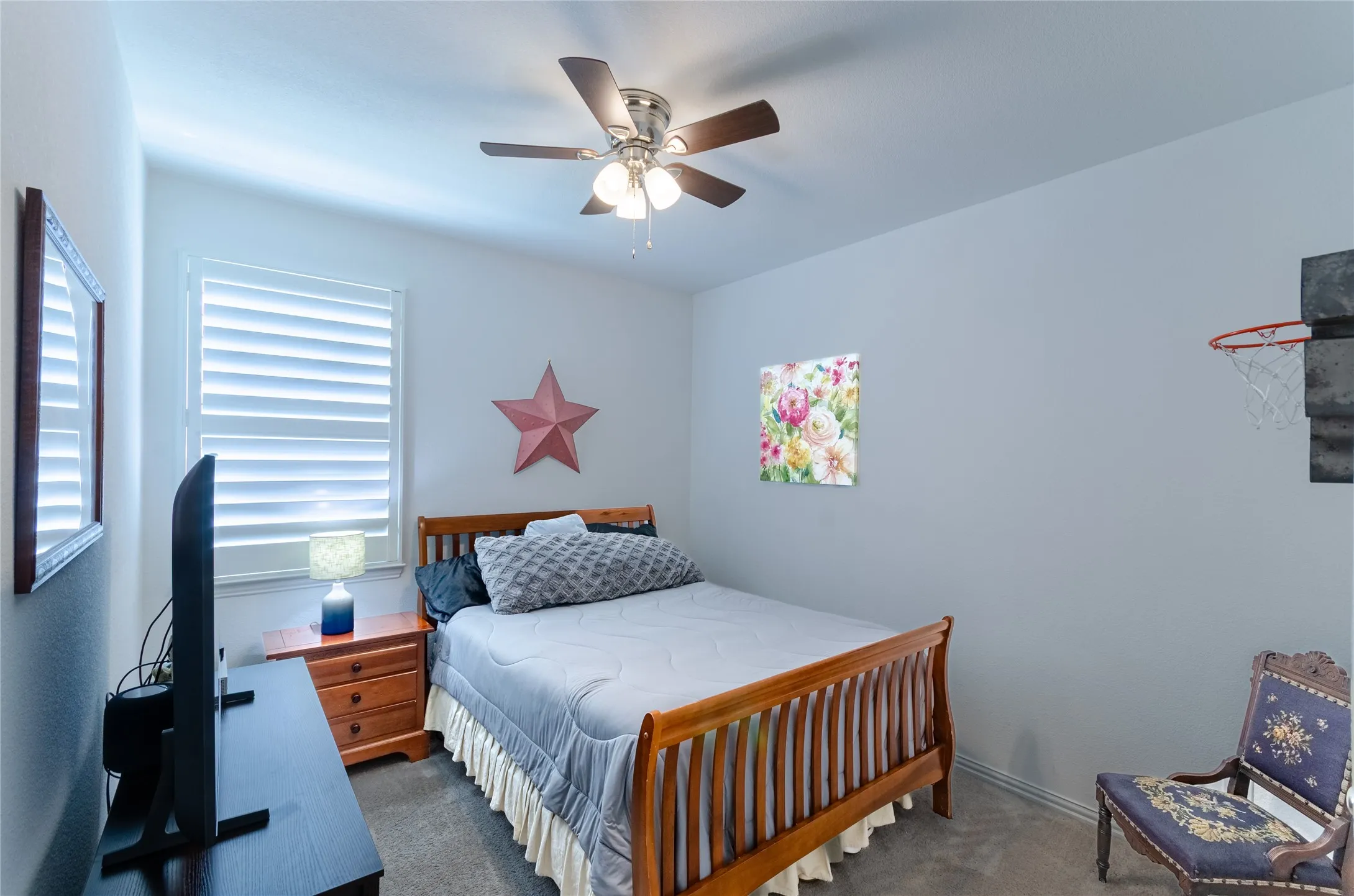 Spacious living area featuring wood-finish flooring, a ceiling fan with integrated lighting, and multiple windows with horizontal blinds
