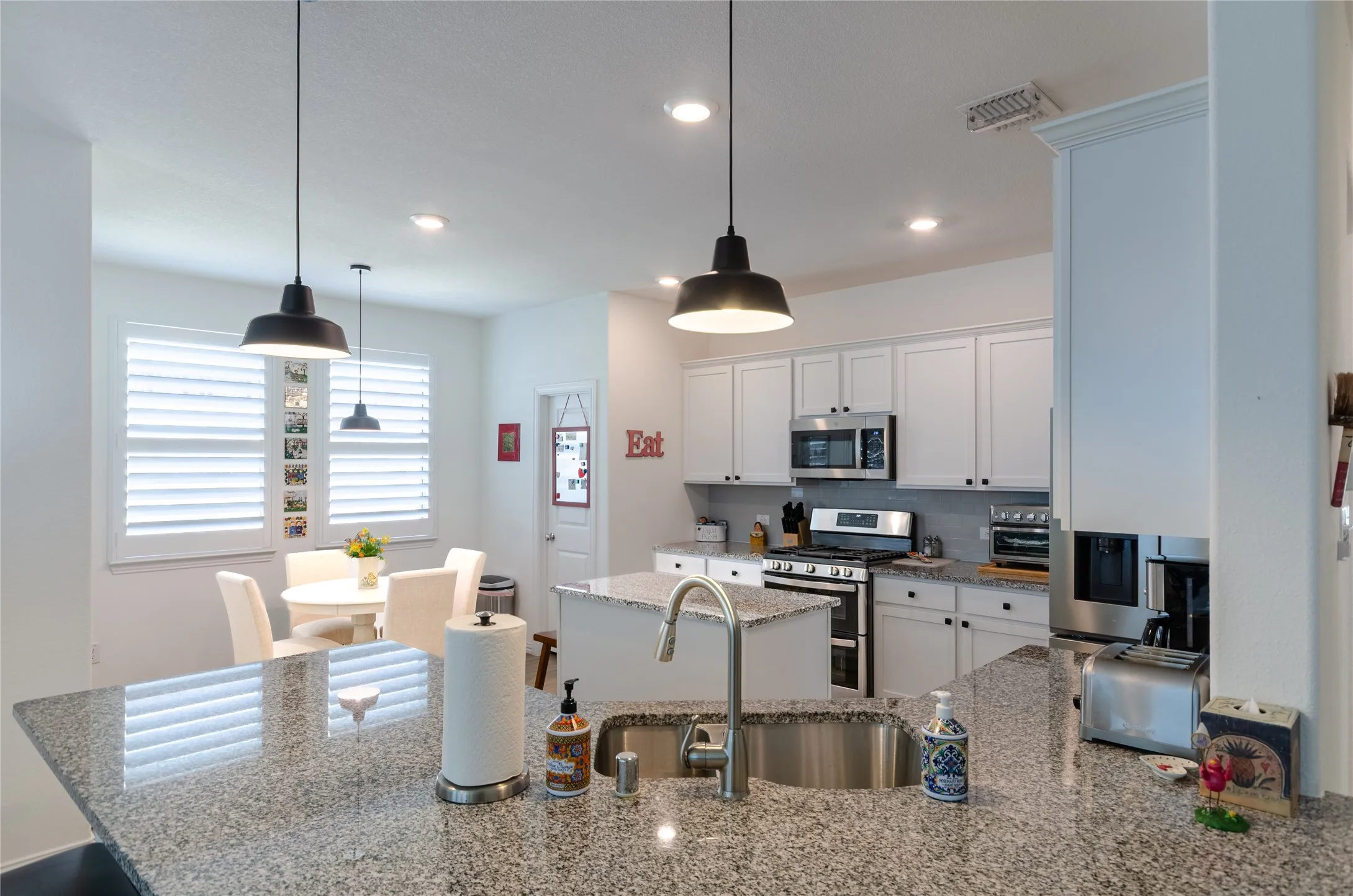 Kitchen featuring granite countertops, stainless steel appliances, white cabinetry, a kitchen island, and recessed lighting