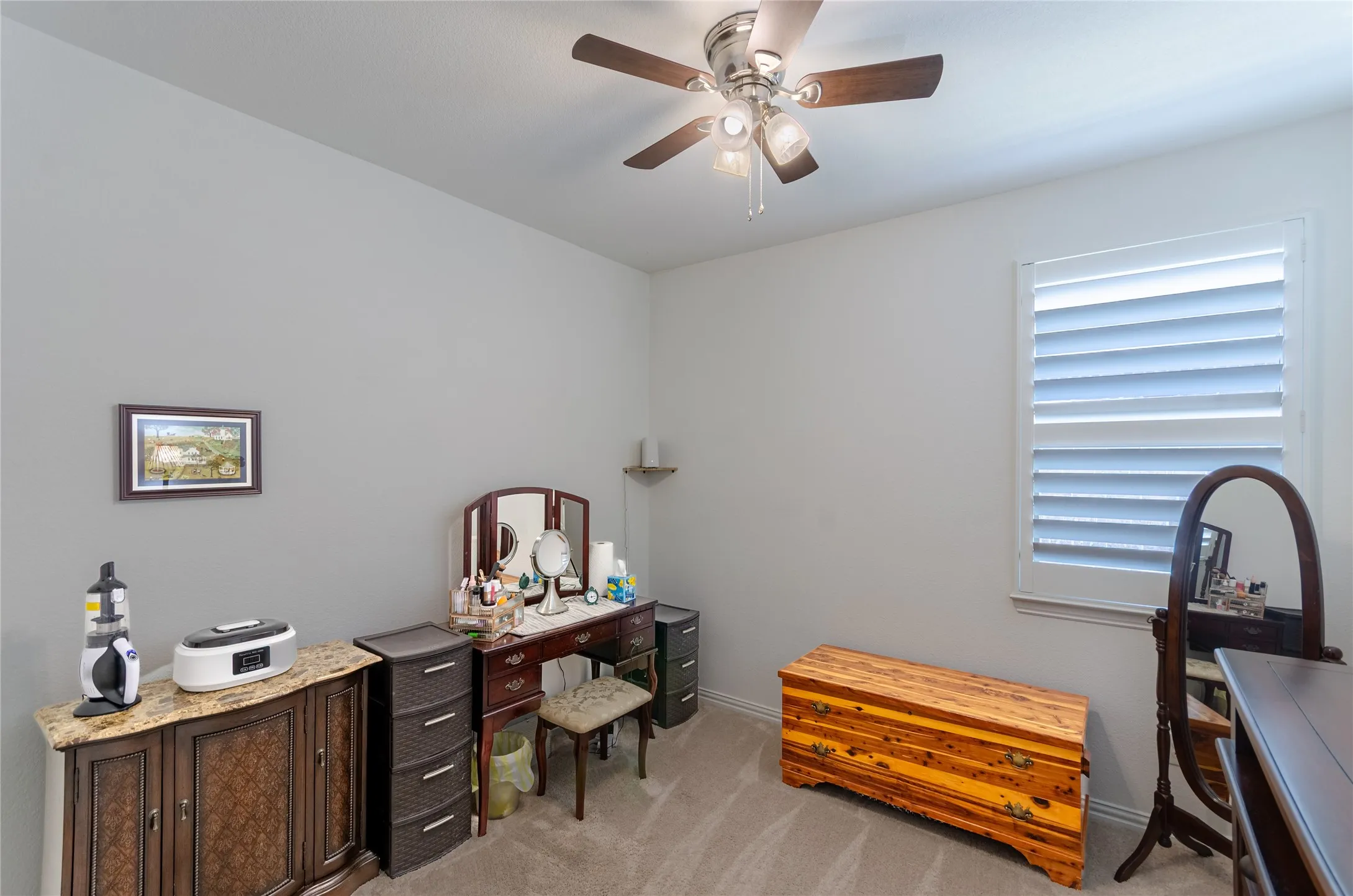 Wood-finish flooring with white walls and a pair of windows fitted with white louvered shutters