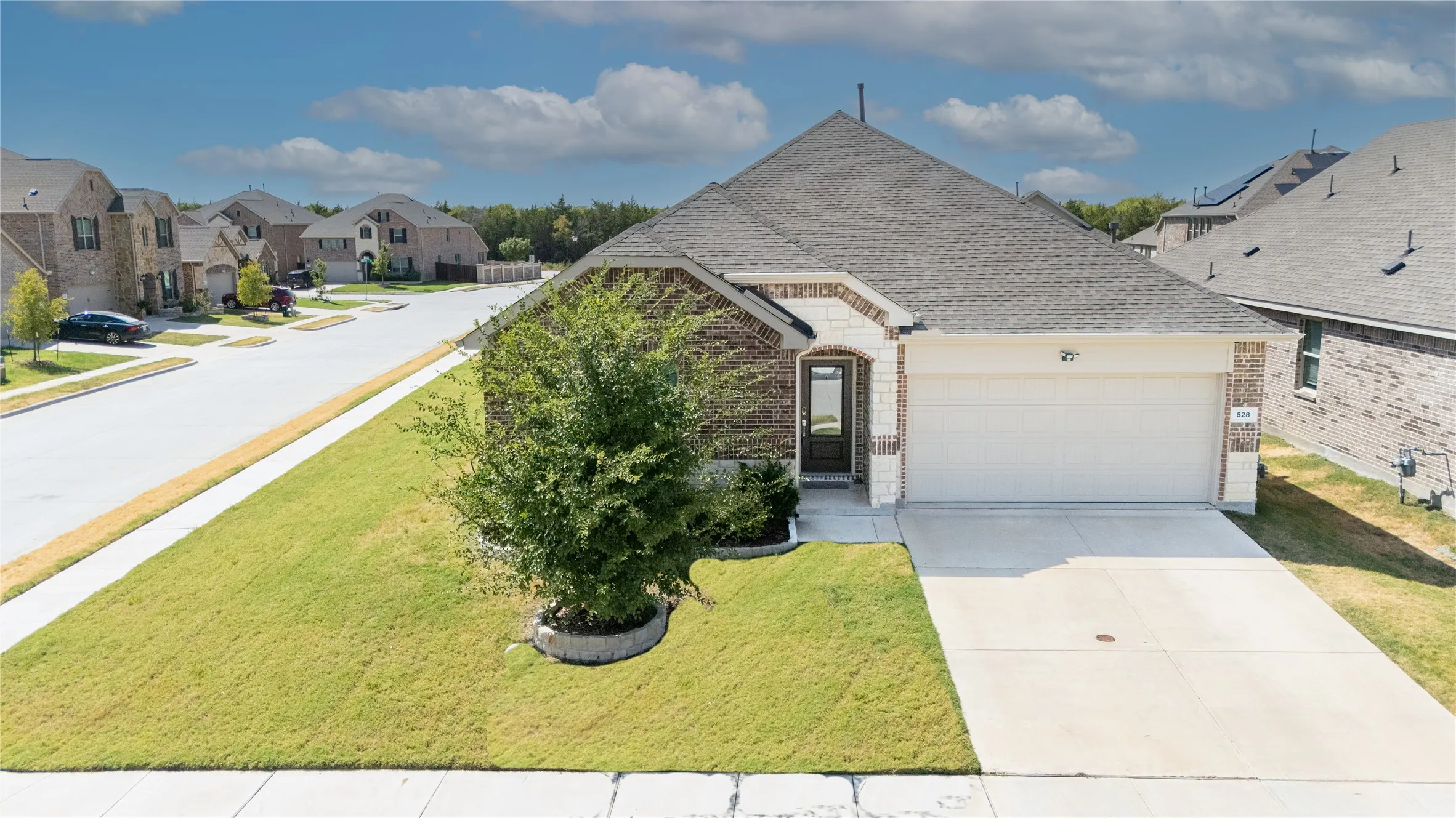 Brick and stone exterior with a two-car garage, concrete driveway, and a front entry with a full-light door