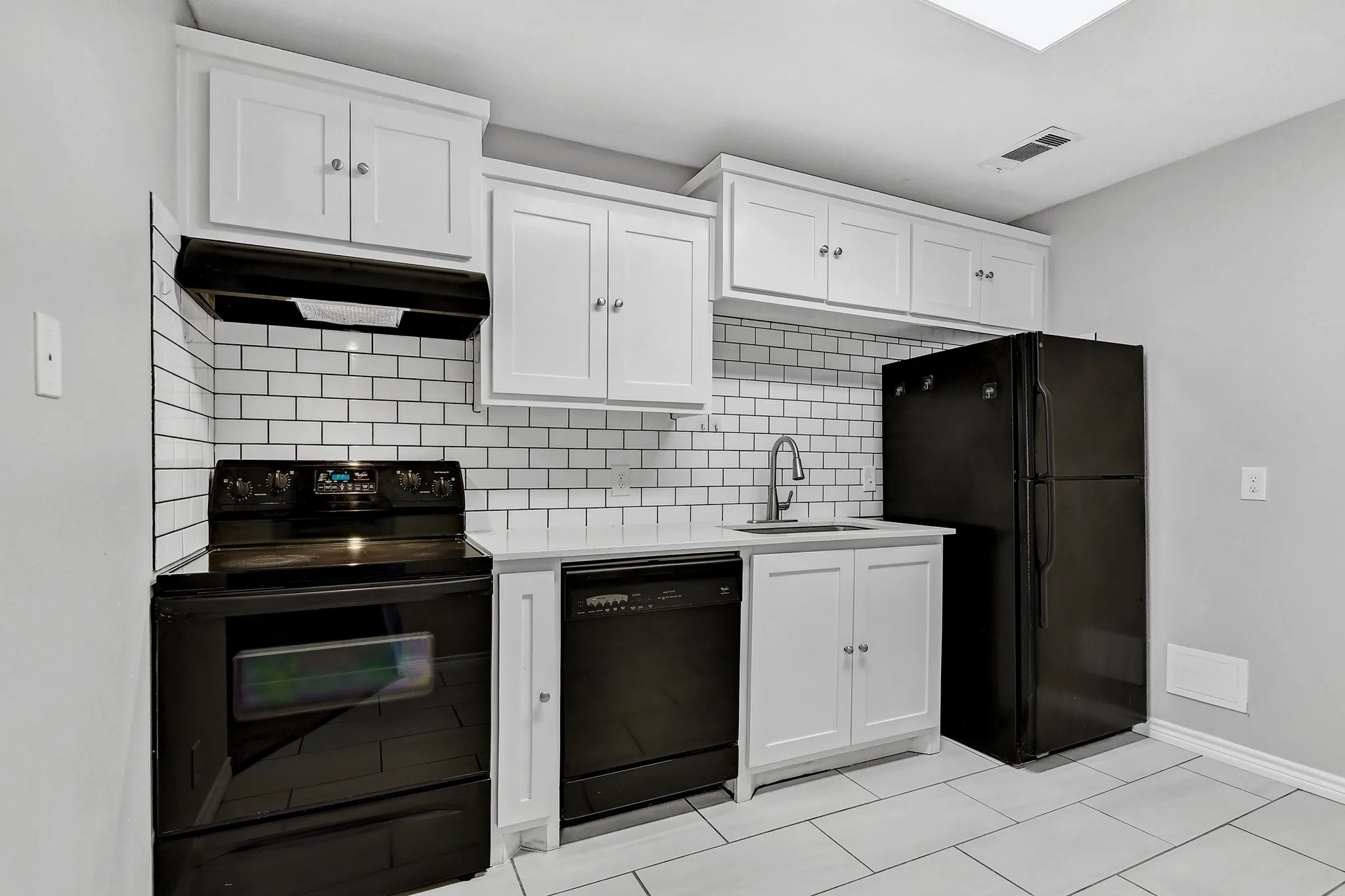 Kitchen with white cabinets, a sink, range hood, tasteful backsplash, and black appliances