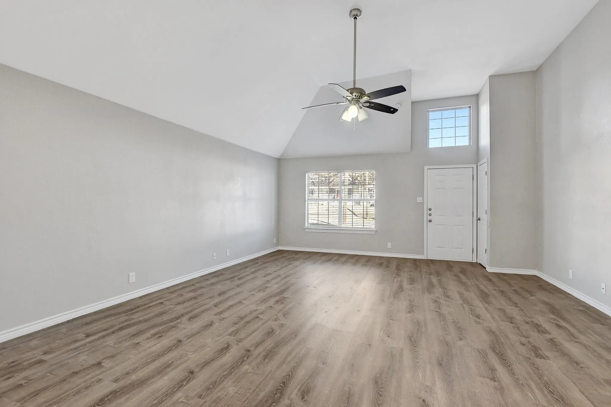 Unfurnished living room with baseboards, a ceiling fan, wood finished floors, and high vaulted ceiling