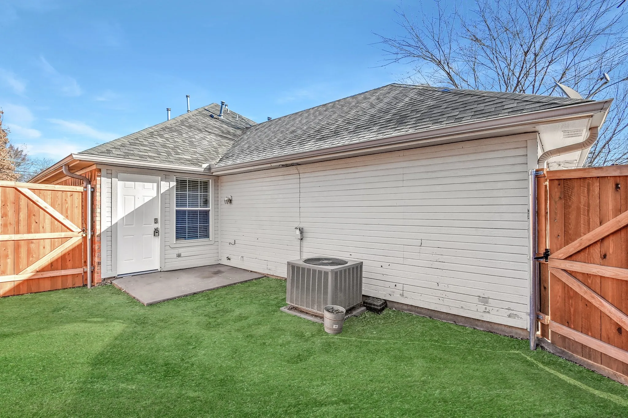 Back of property with a lawn, fence, a shingled roof, and a gate