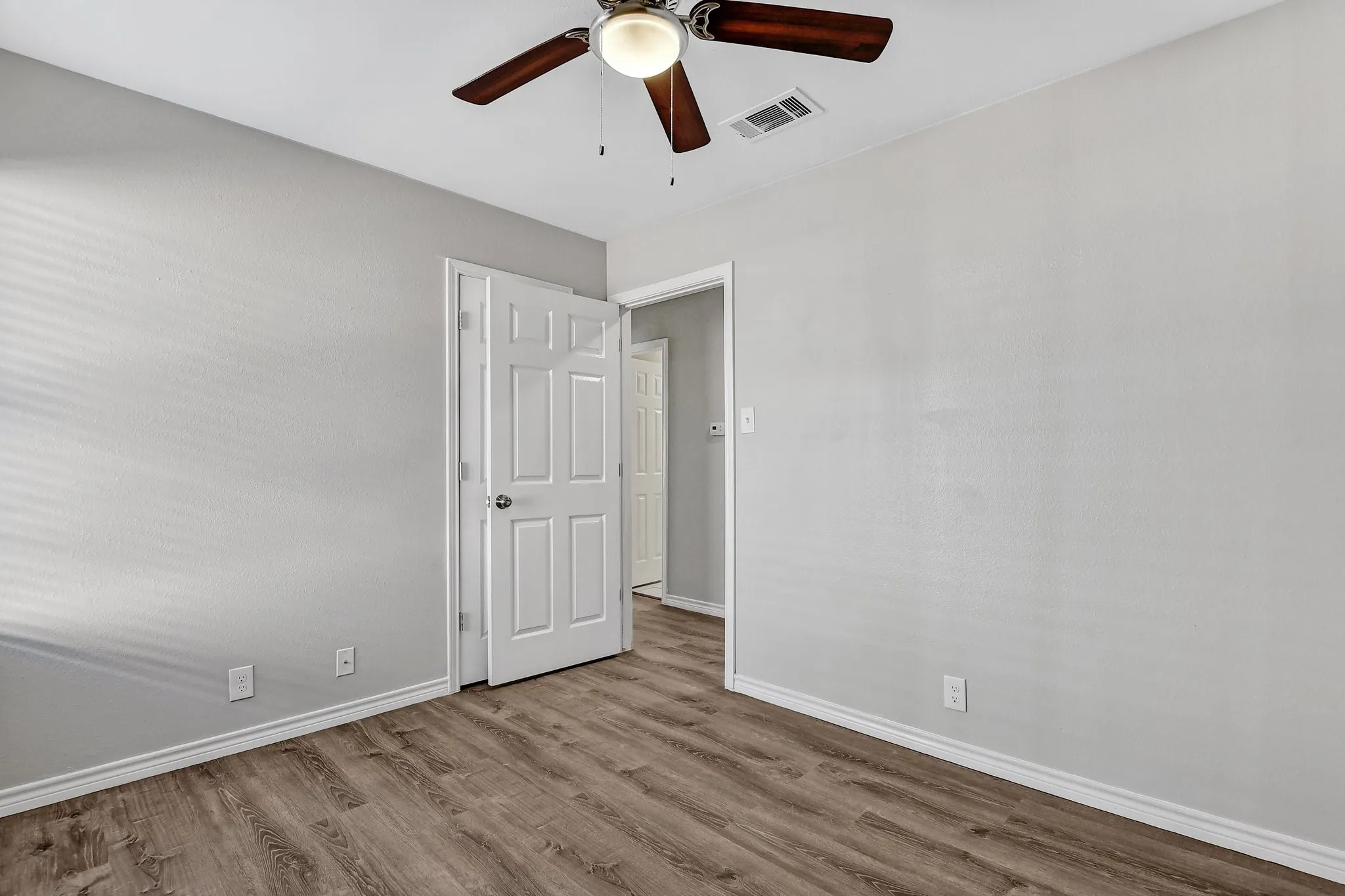 Empty room with baseboards, ceiling fan, wood finished floors, and visible vents