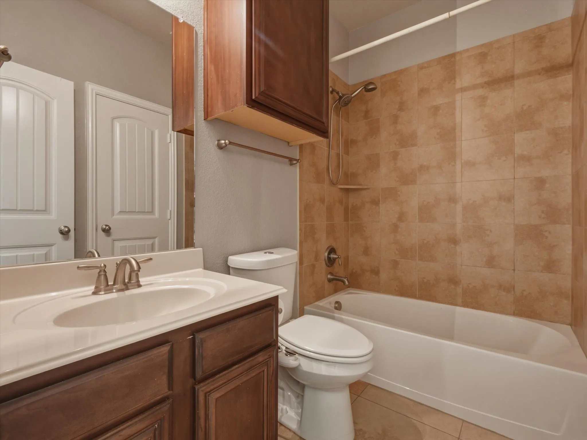 Vanity with integrated sink, wood-finish cabinetry, and brushed nickel fixtures