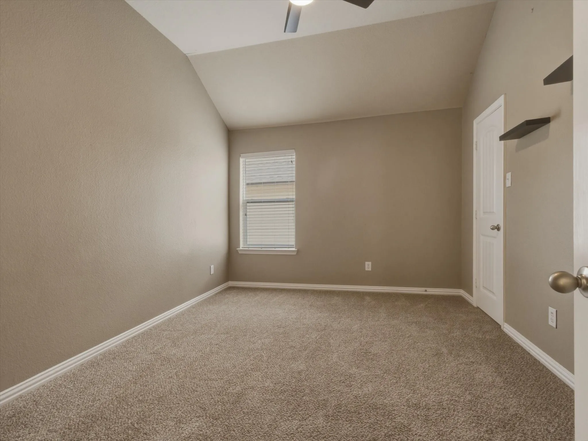 Vaulted ceiling, ceiling fan, neutral carpet flooring
