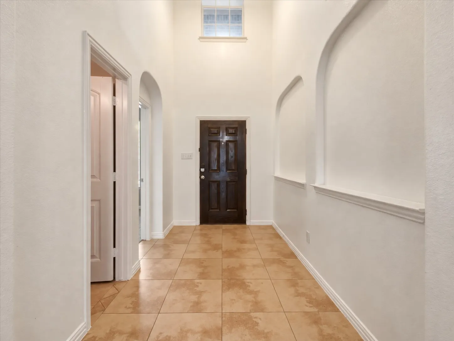 Two-story entry with tile flooring, transom window, and architectural wall arches