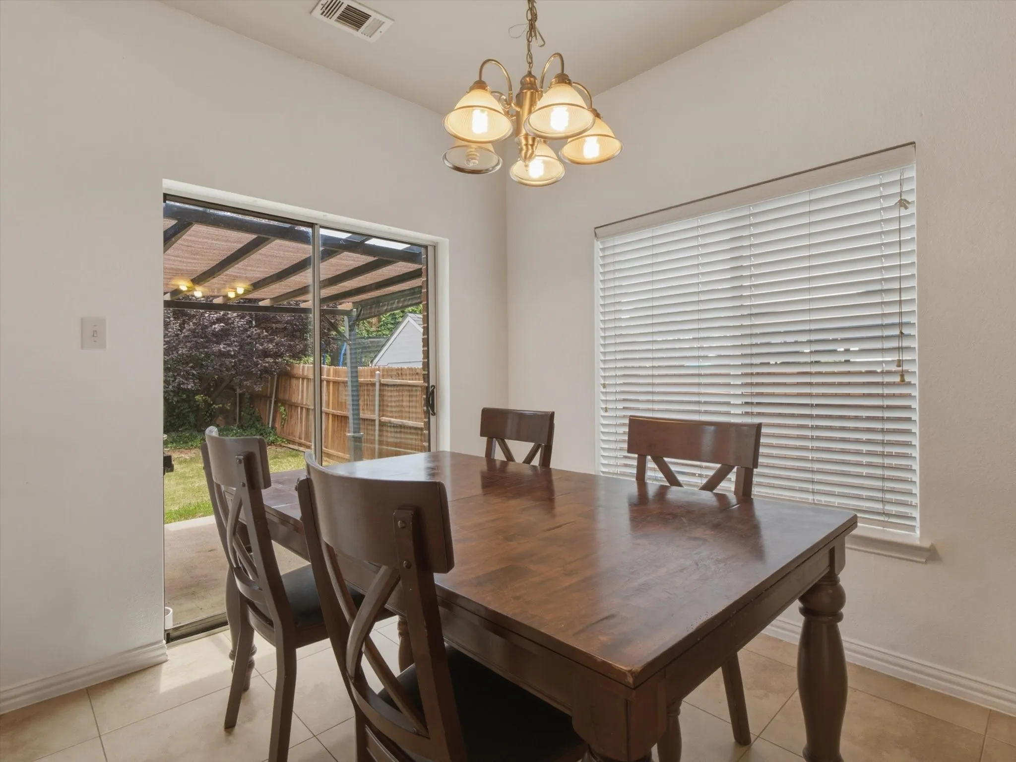 Dining area featuring brass chandelier, sliding glass door, and tiled flooring