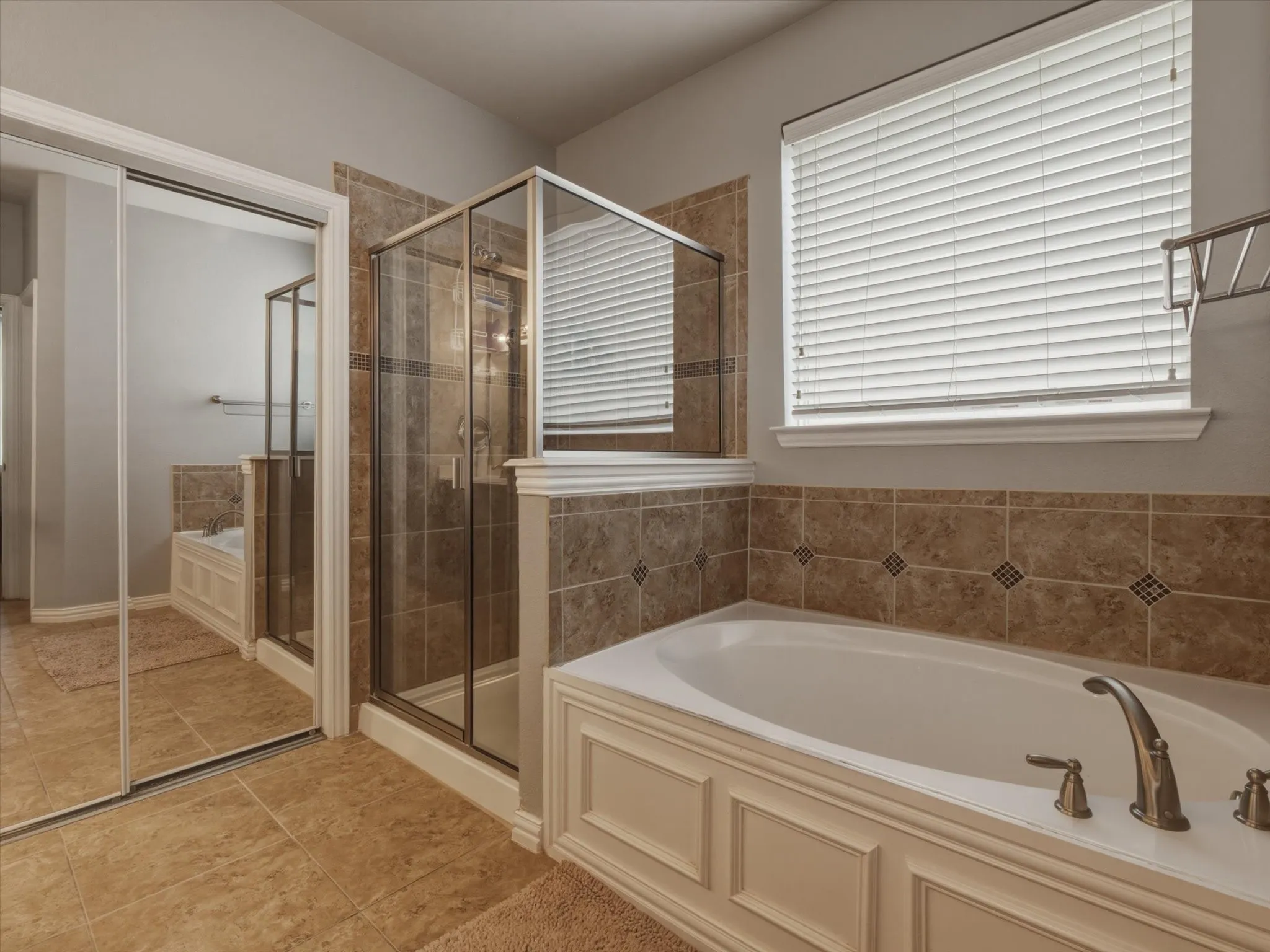 Tiled flooring and wall accents complement the soaking tub with paneling detail