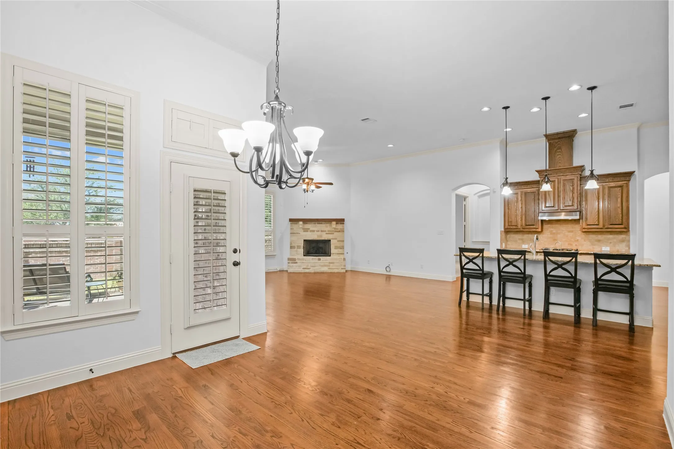 Hardwood flooring throughout, a stone-surround fireplace, and a kitchen island with pendant lighting