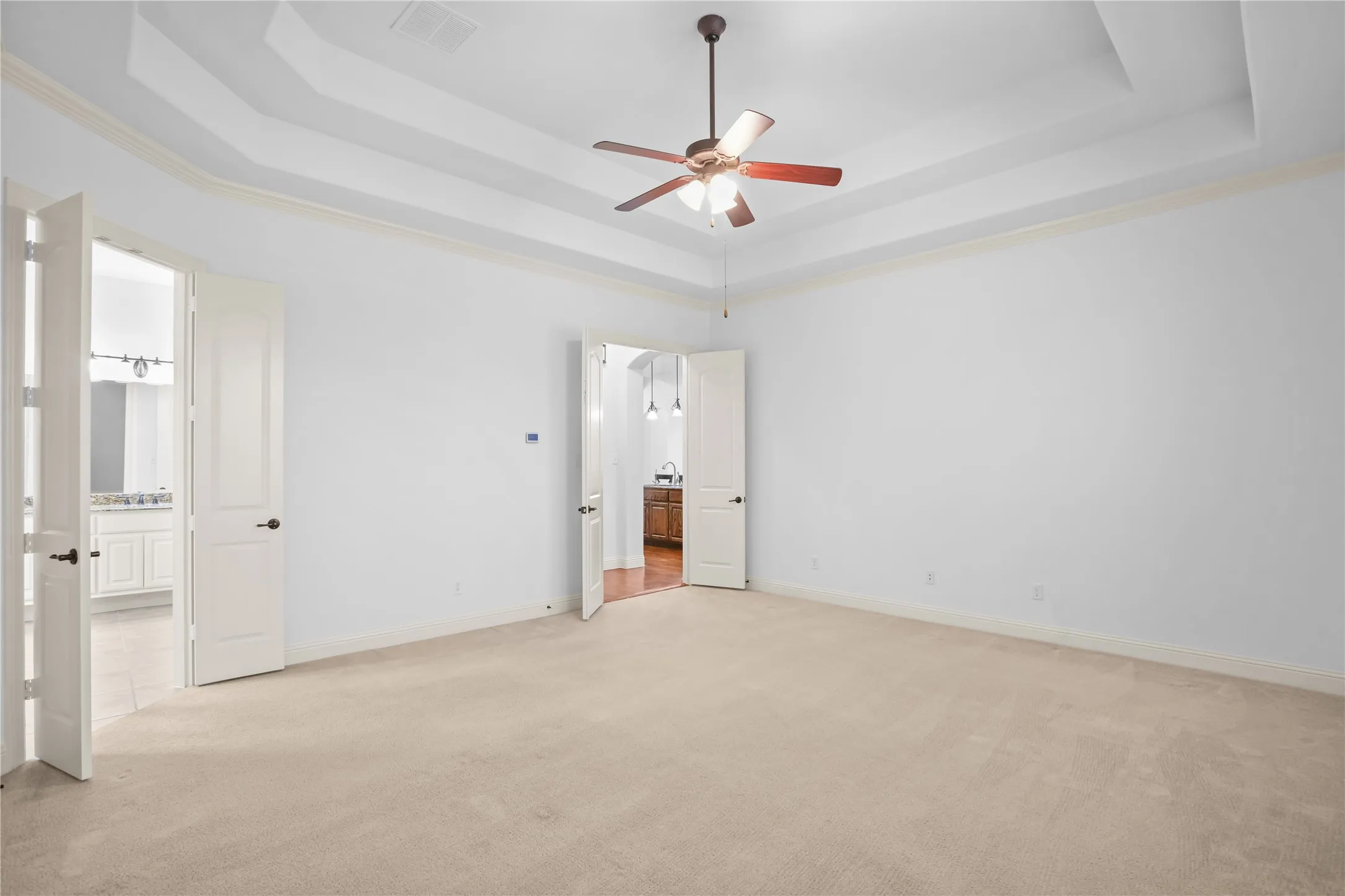Recessed ceiling with crown molding and ceiling fan, carpeted flooring, and French doors