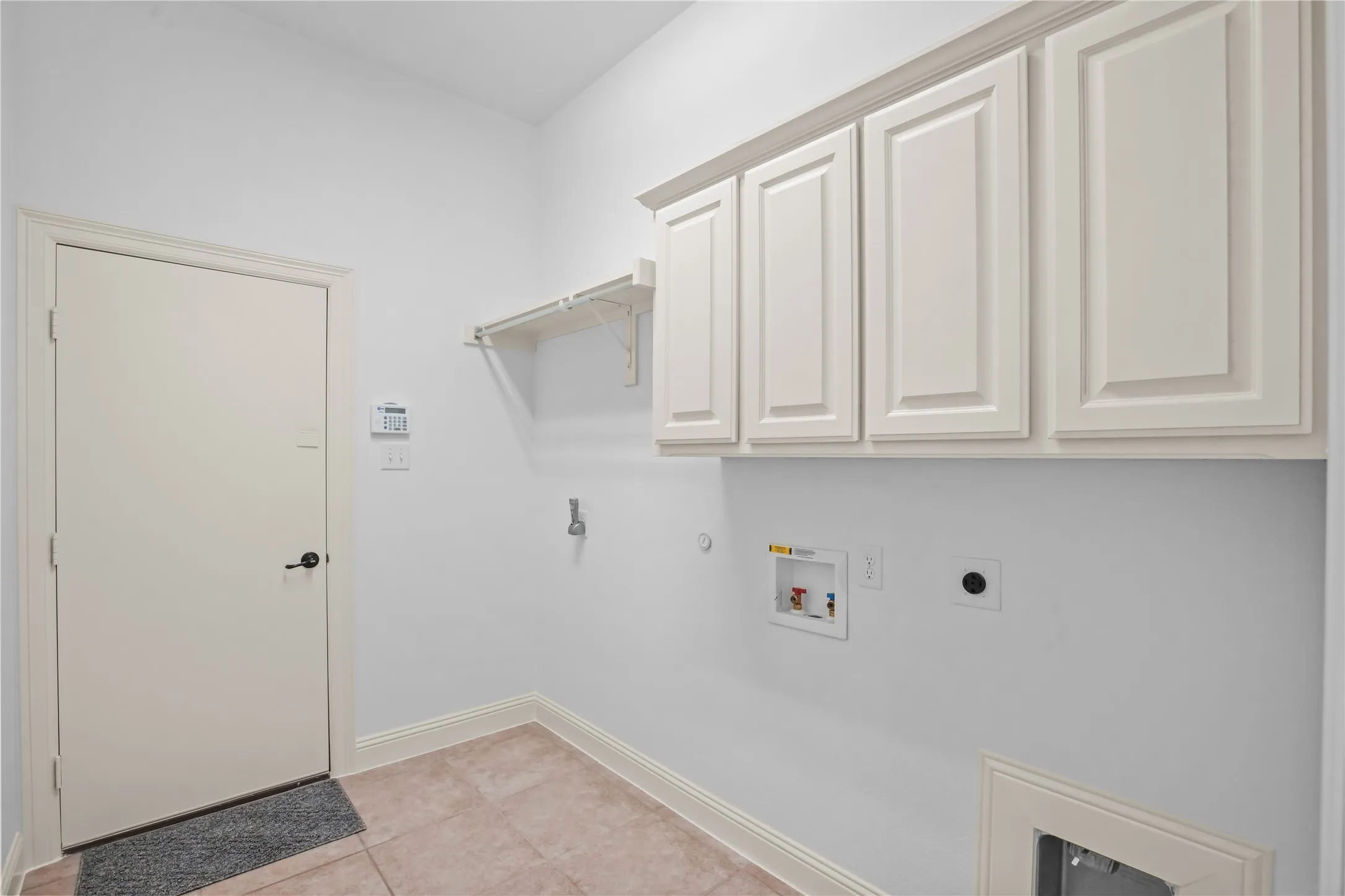 Built-in upper cabinetry, wall-mounted shelving, tiled flooring, and room for an extra fridge