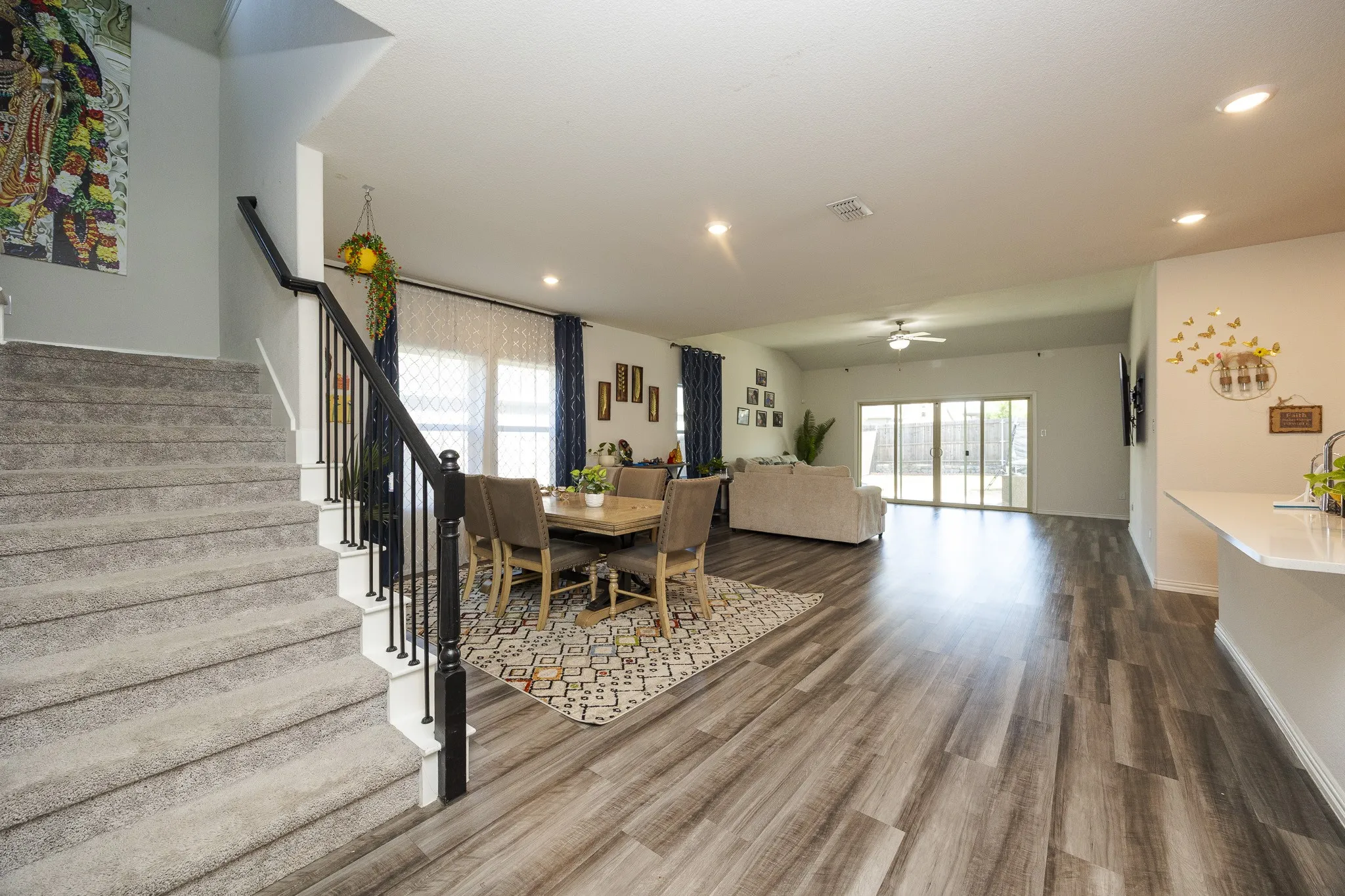 Staircase with carpeted treads and wrought iron balusters, wood-finish flooring, recessed lighting, and sliding glass doors