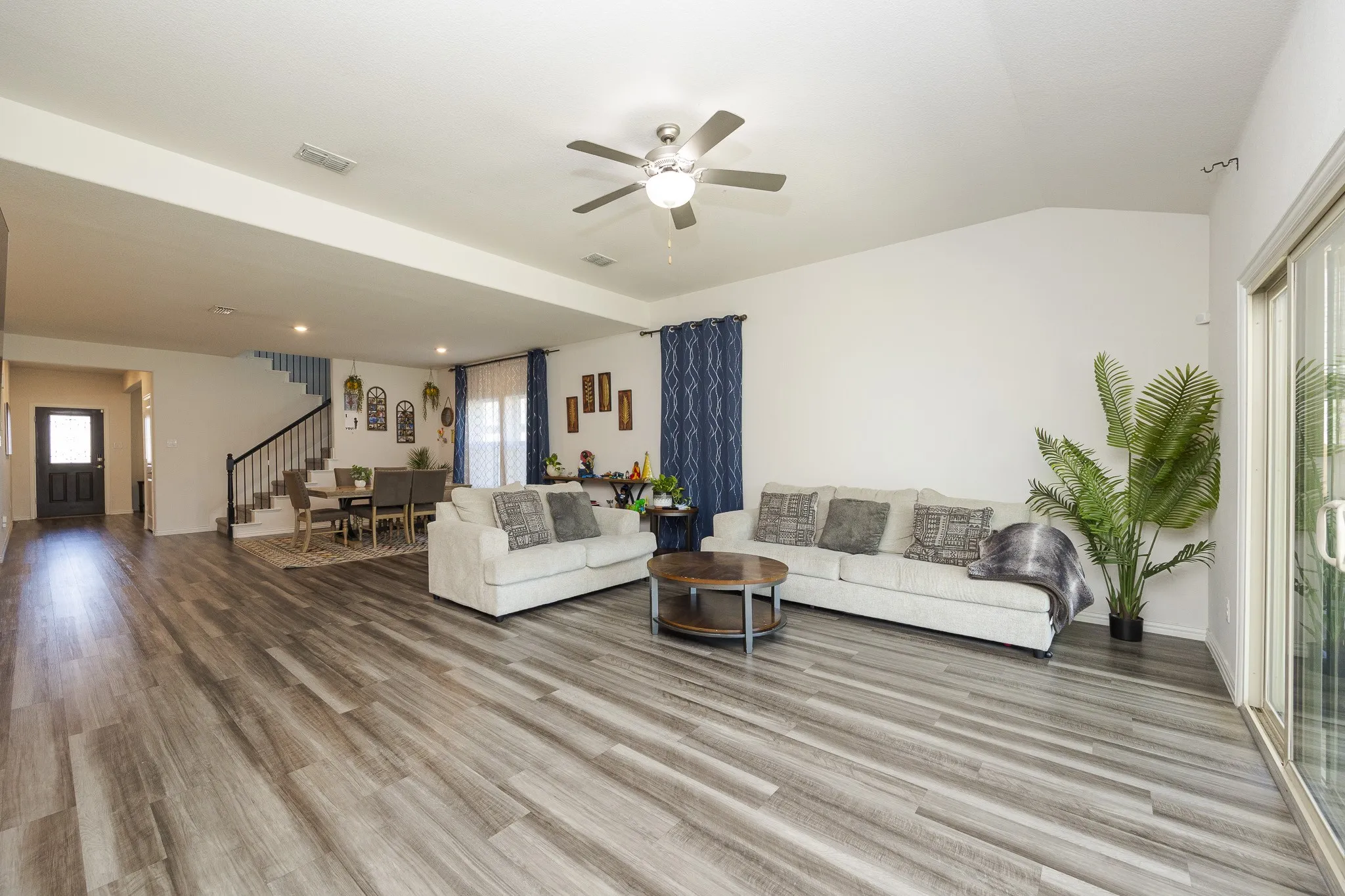 Spacious living area featuring wood-finish flooring, vaulted ceilings, and a ceiling fan