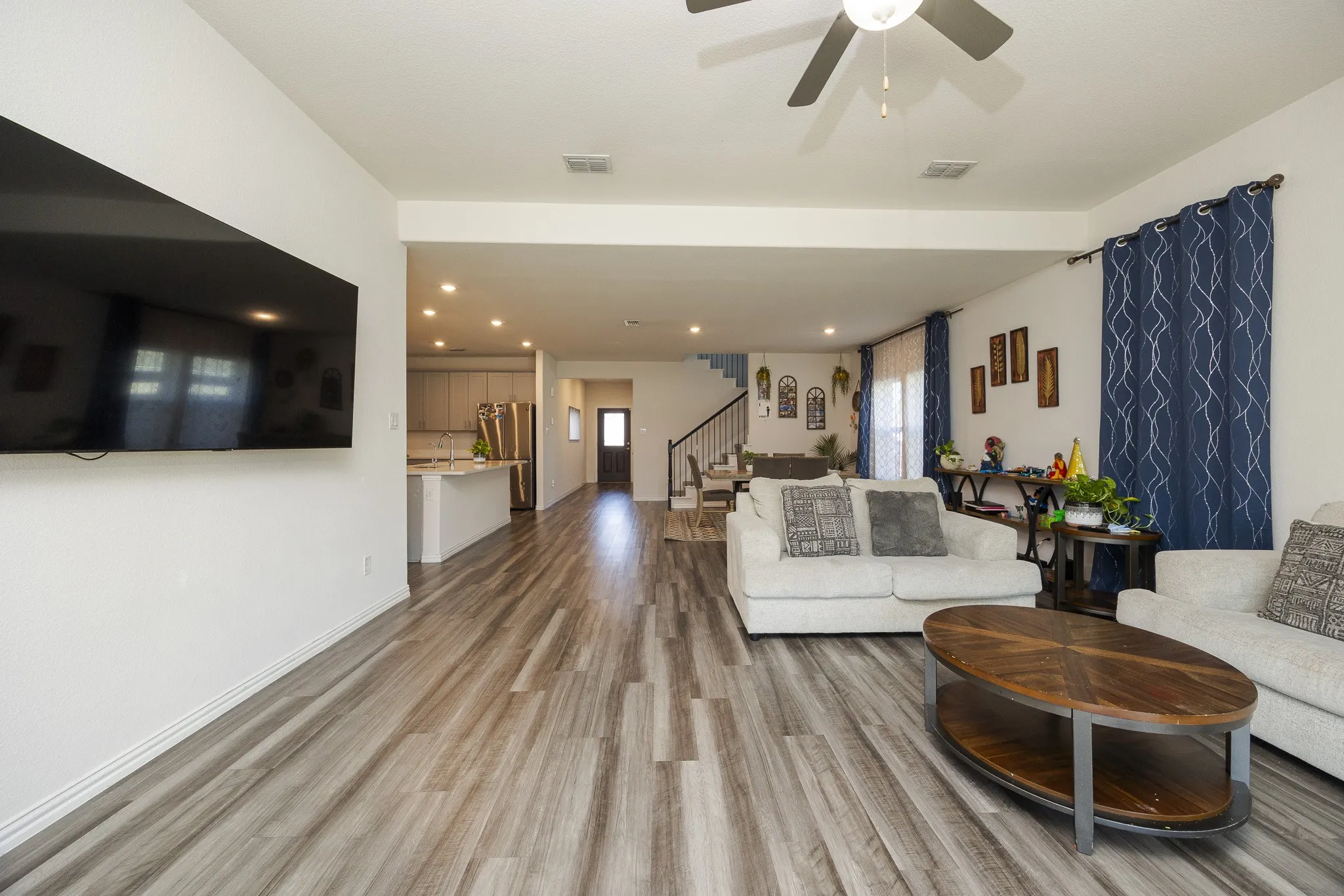 Open-concept living area featuring wood-finish flooring, recessed lighting, a ceiling fan, and a kitchen with an island