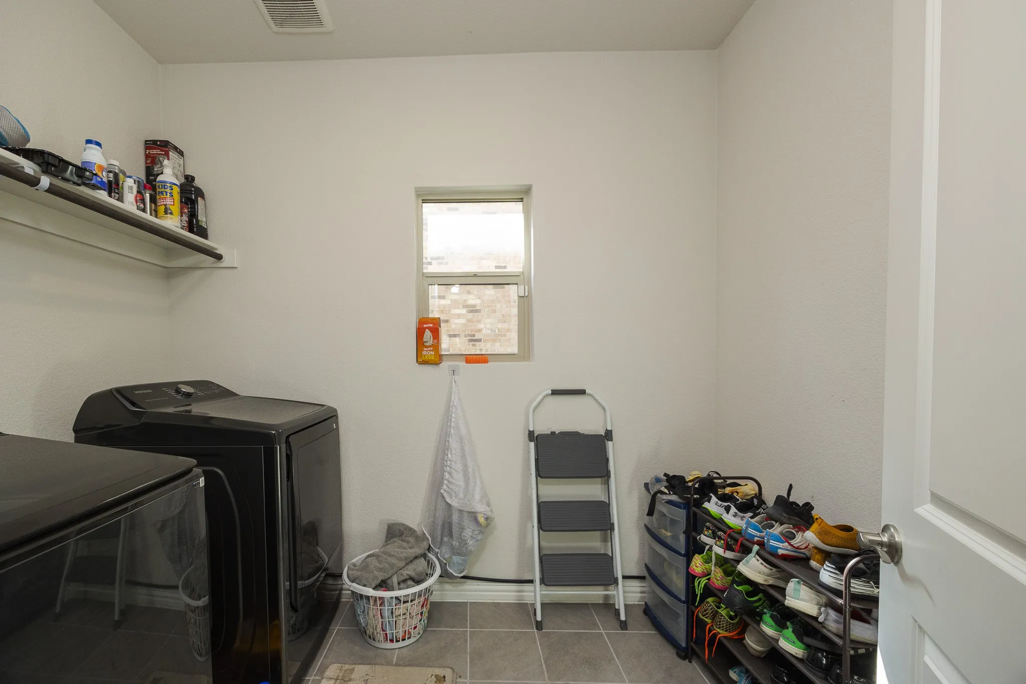 Window with natural light, wall-mounted shelving, and tile flooring