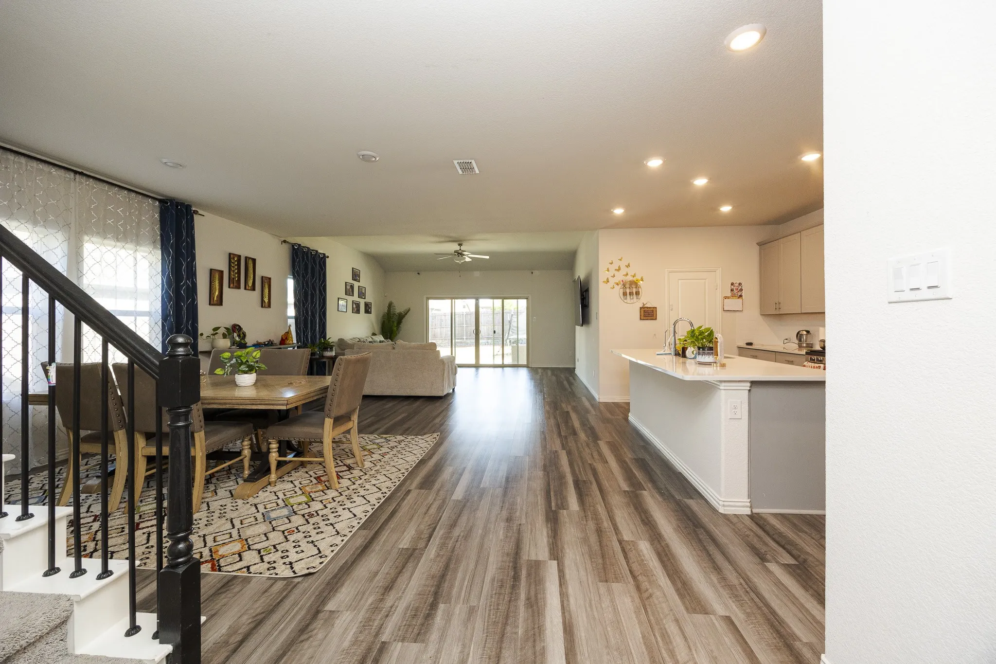 Open-concept interior featuring wood-finish flooring, recessed lighting, and a kitchen island with a built-in sink