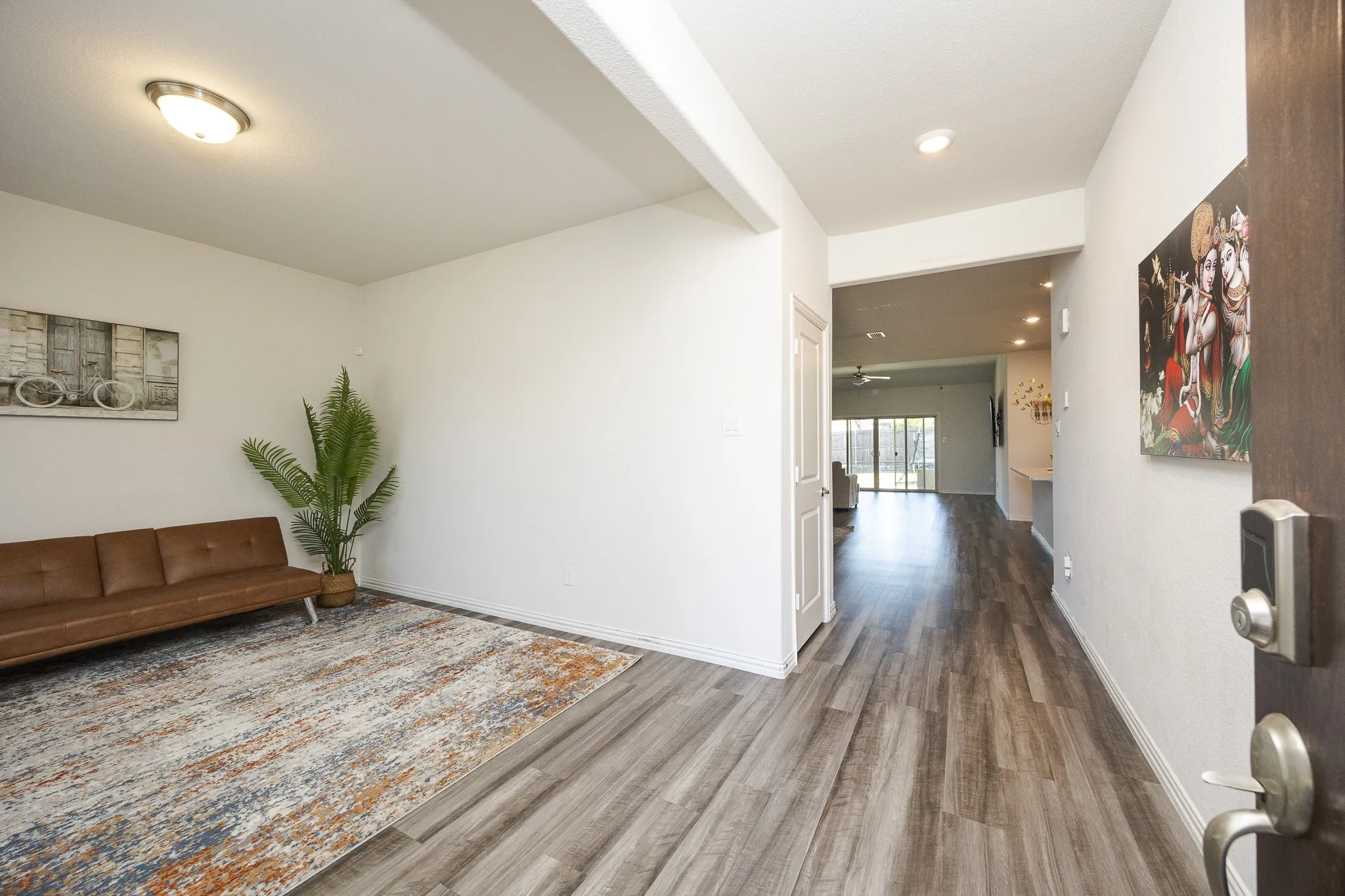 Wood-finish flooring throughout, recessed ceiling lighting, and a white interior door