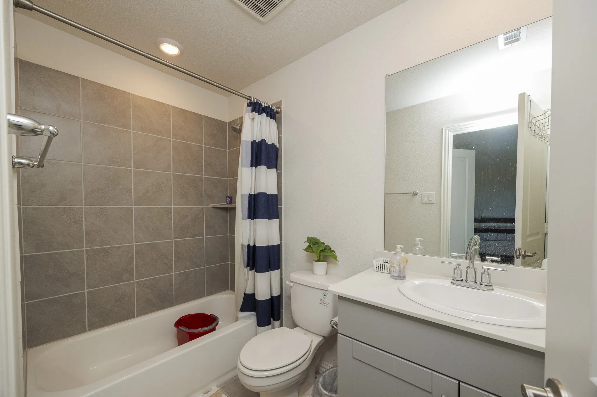 Contemporary vanity with a white countertop and oval sink, set against a tiled bath and shower combination