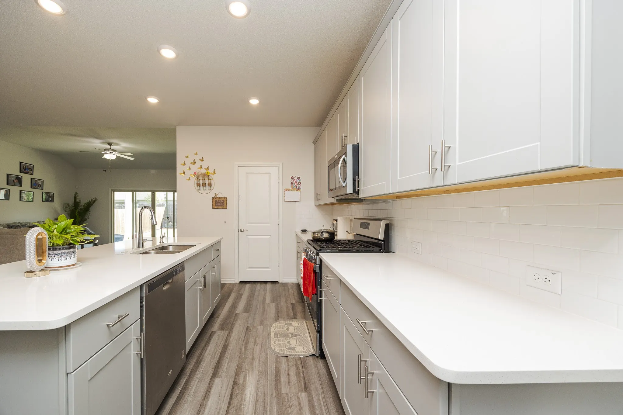 Contemporary kitchen featuring light gray cabinetry, stainless steel appliances, white countertops, a subway tile backsplash, and recessed lighting