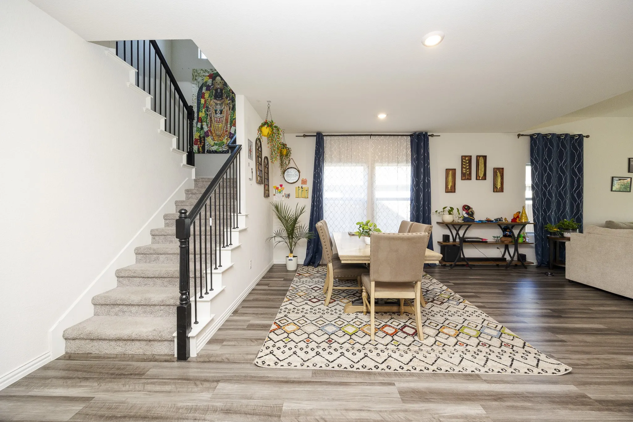 Wood-finish flooring, recessed lighting, carpeted staircase with black balusters, and white interior walls
