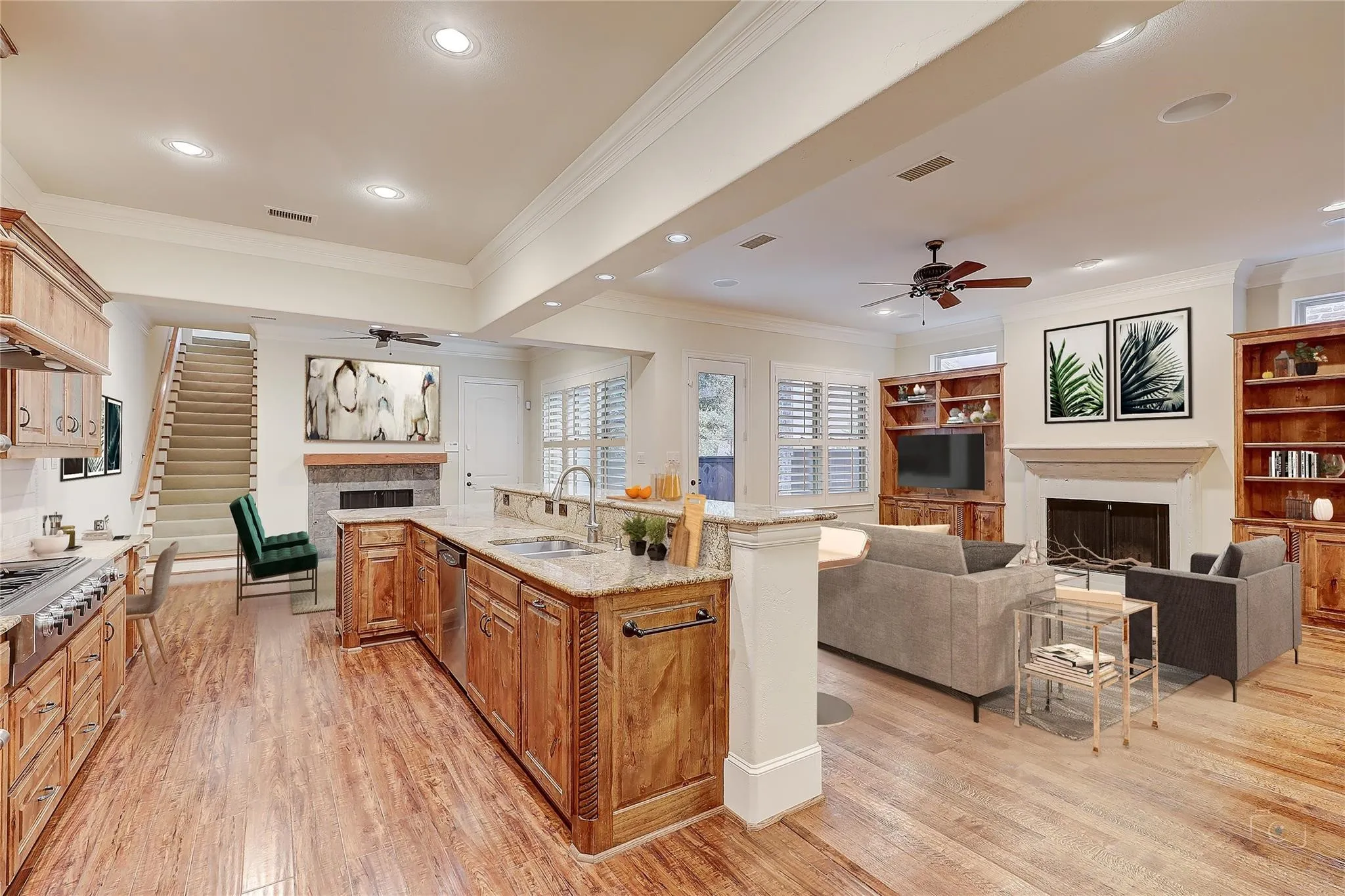 Wood-finish flooring throughout, kitchen with light wood cabinetry and granite countertops, built-in shelving, stone fireplace, and recessed lighting