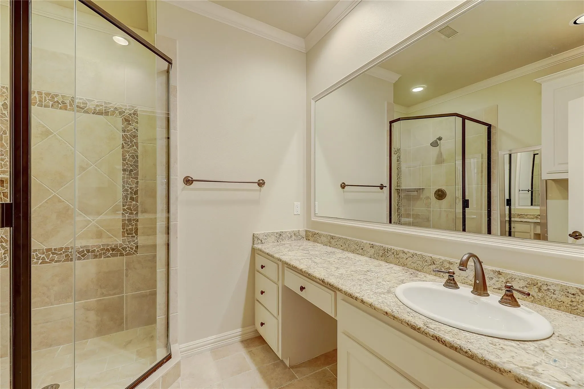 Walk-in shower with clear glass enclosure, custom tile work, and bronze-finish hardware