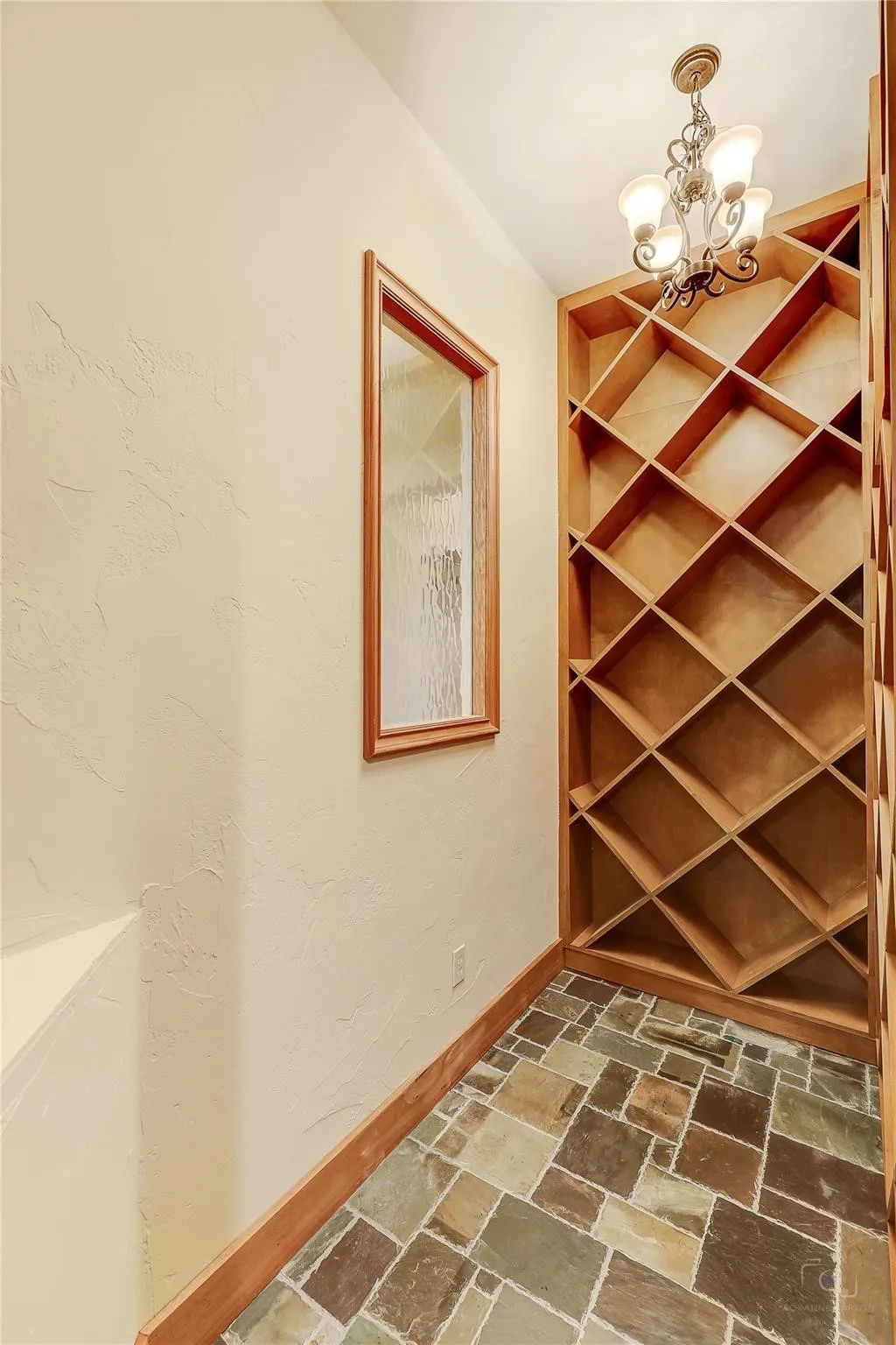 Built-in wine storage, multi-toned slate flooring, decorative chandelier, textured wall finish, and a wood-framed window