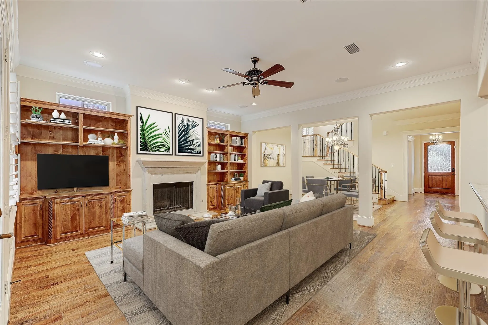 Hardwood flooring throughout, stone fireplace with hearth, recessed lighting, and built-in cabinetry with integrated shelving