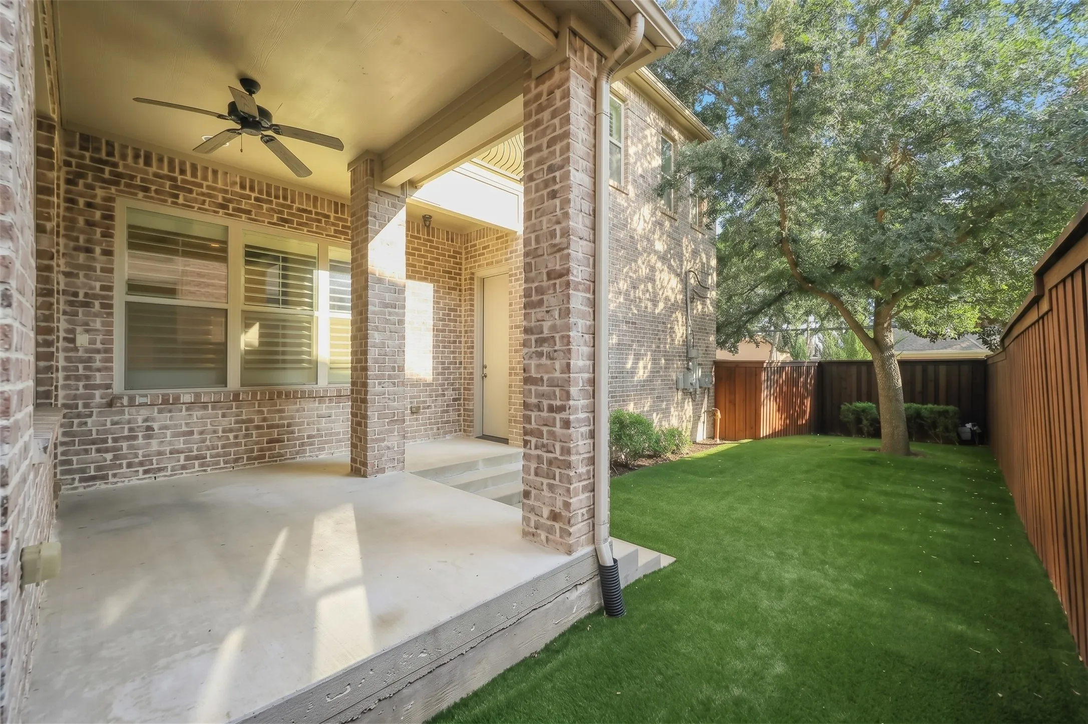 Covered patio with a ceiling fan, brick exterior, and concrete flooring
