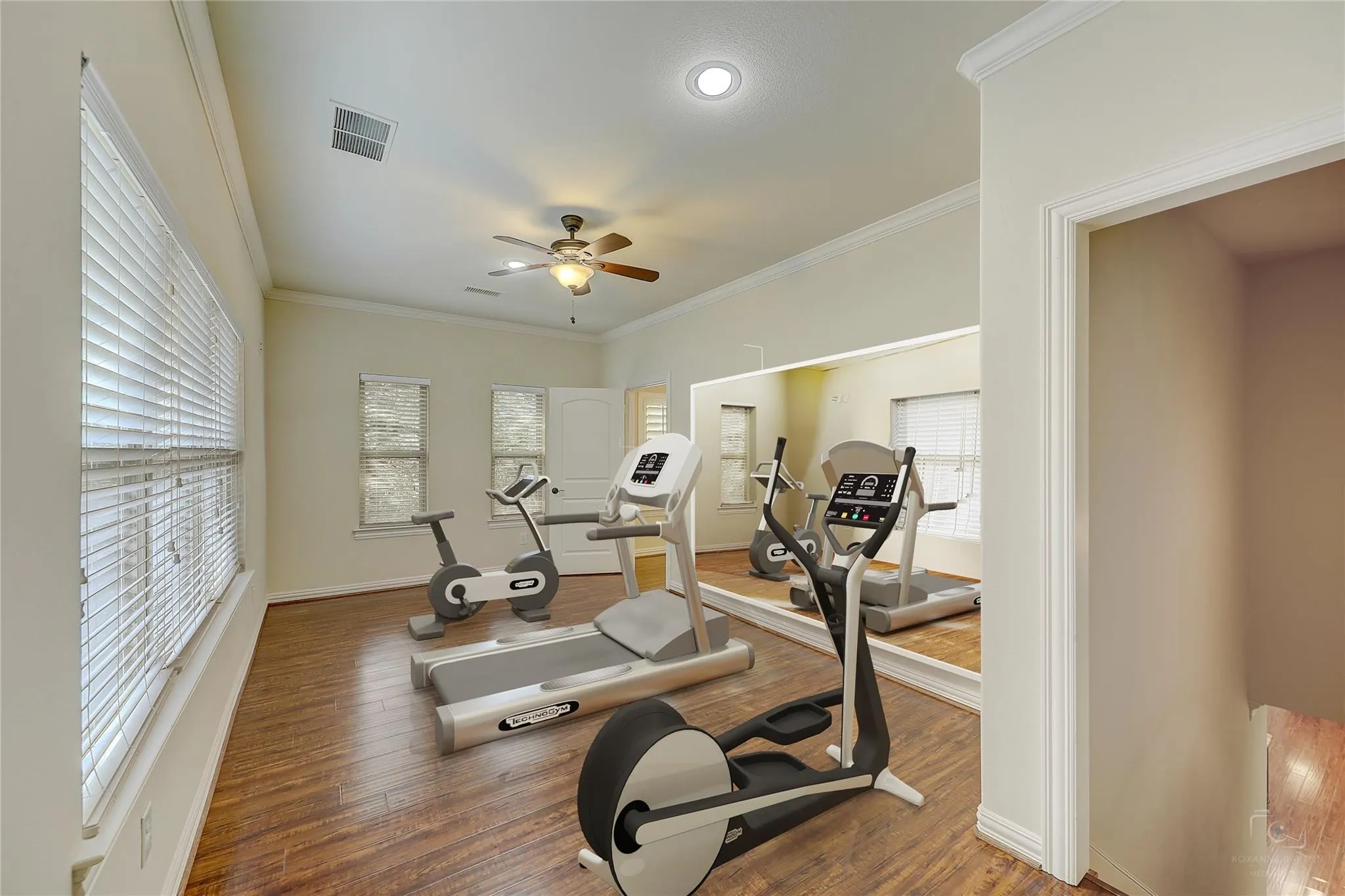 Room with wood-finish flooring, a ceiling fan, and multiple windows