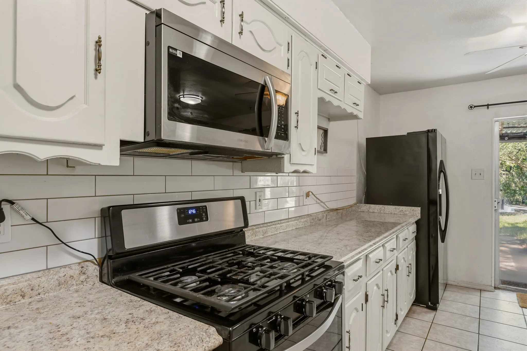 The kitchen has a gas range and a stainless steel microwave.