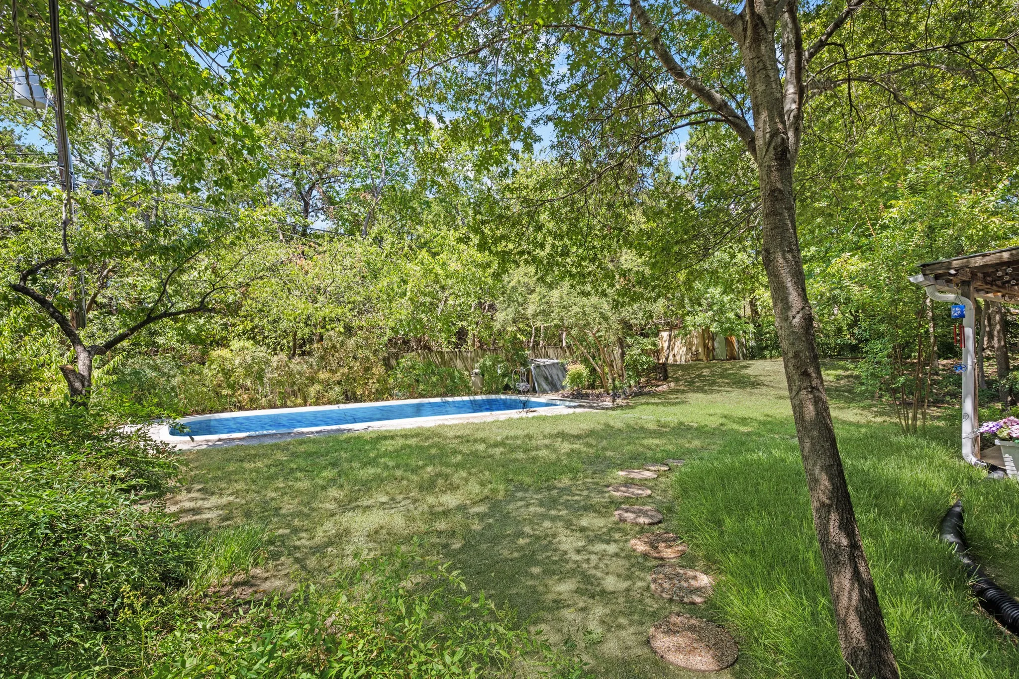 Welcome to this tree-shaded home. The pool is virtually filled with water.