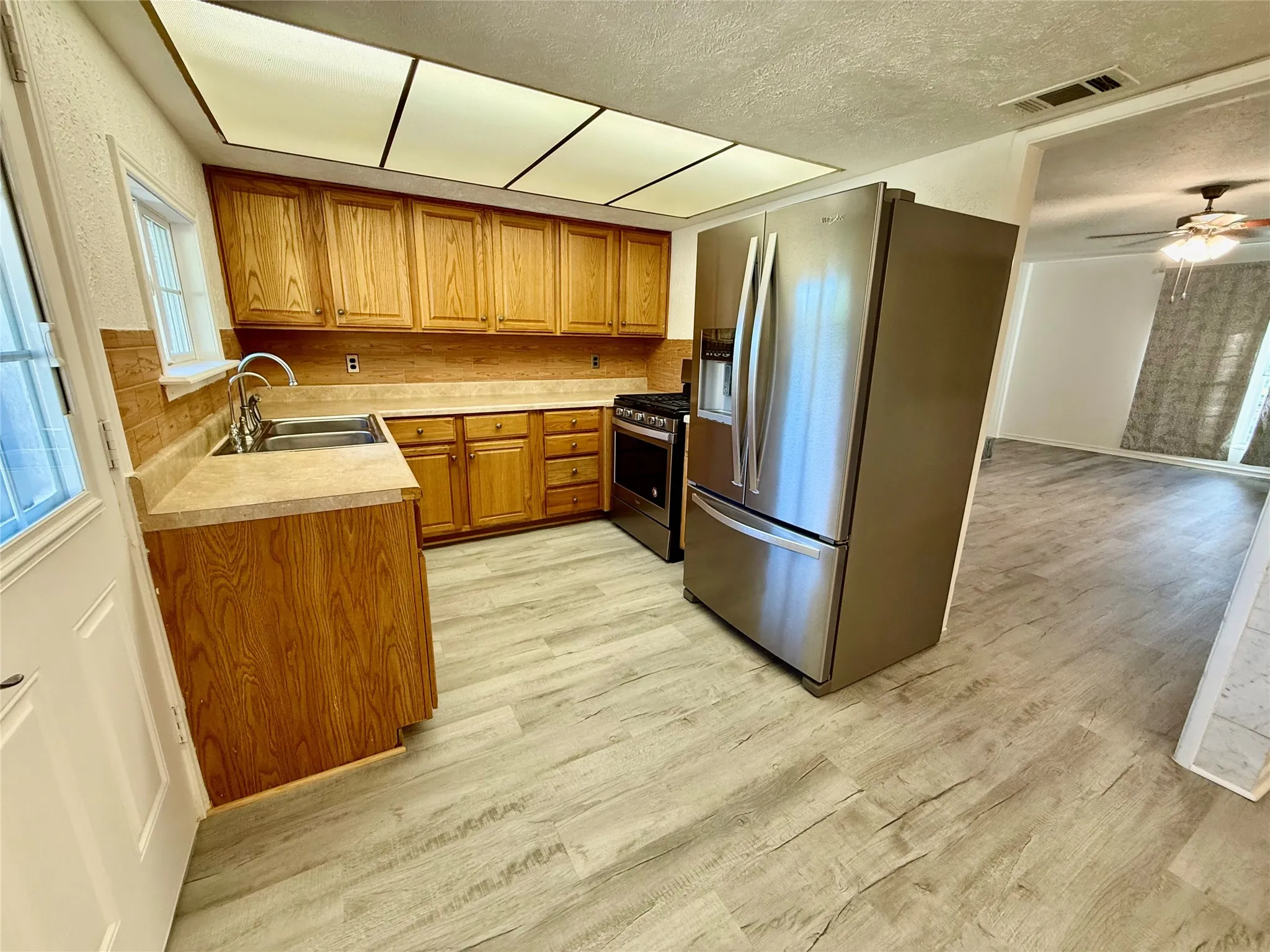 Kitchen featuring wood cabinetry, stainless steel refrigerator, stainless steel range, and wood-finish flooring