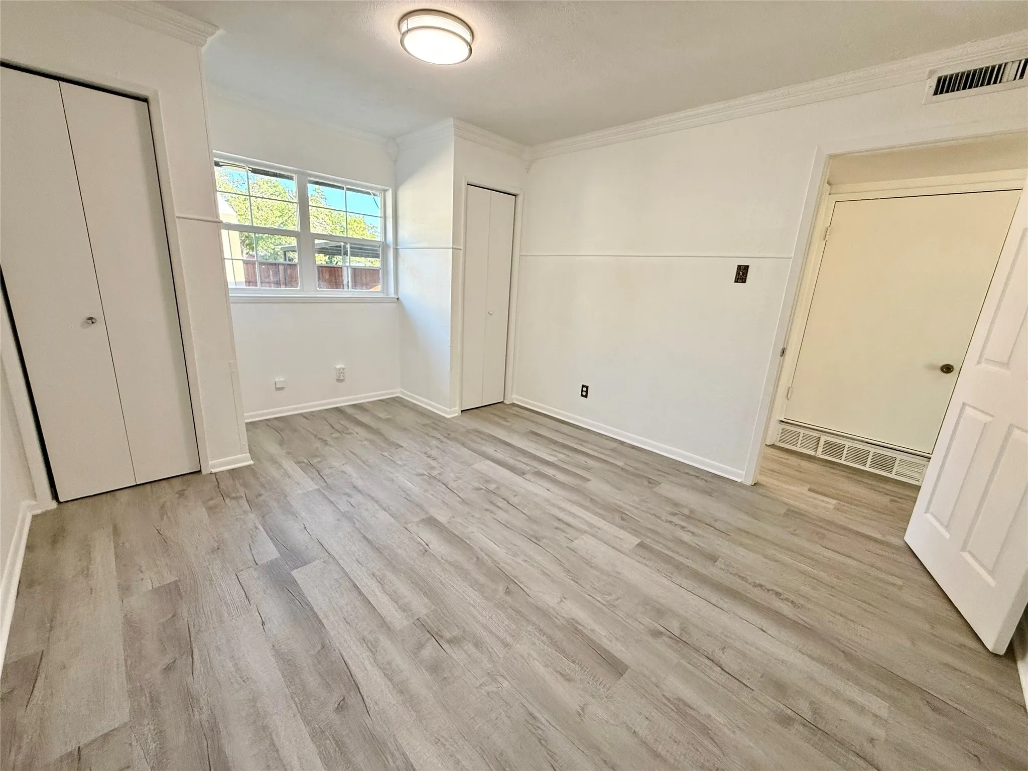 Wood-finish flooring, crown molding, and two bi-fold door closets
