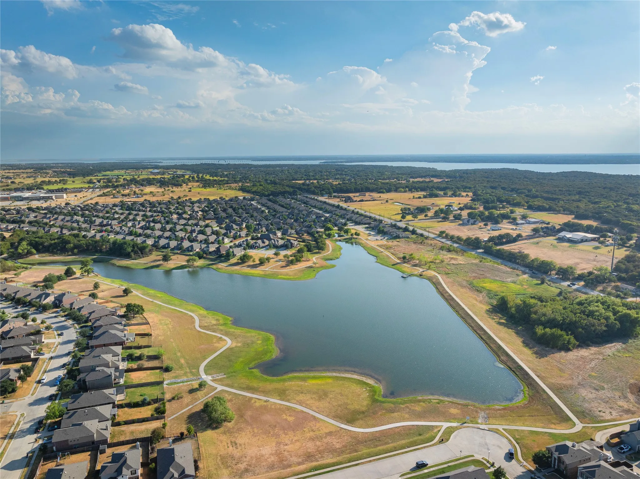 Expansive neighborhood with a central pond, surrounding green spaces, and paved walking paths