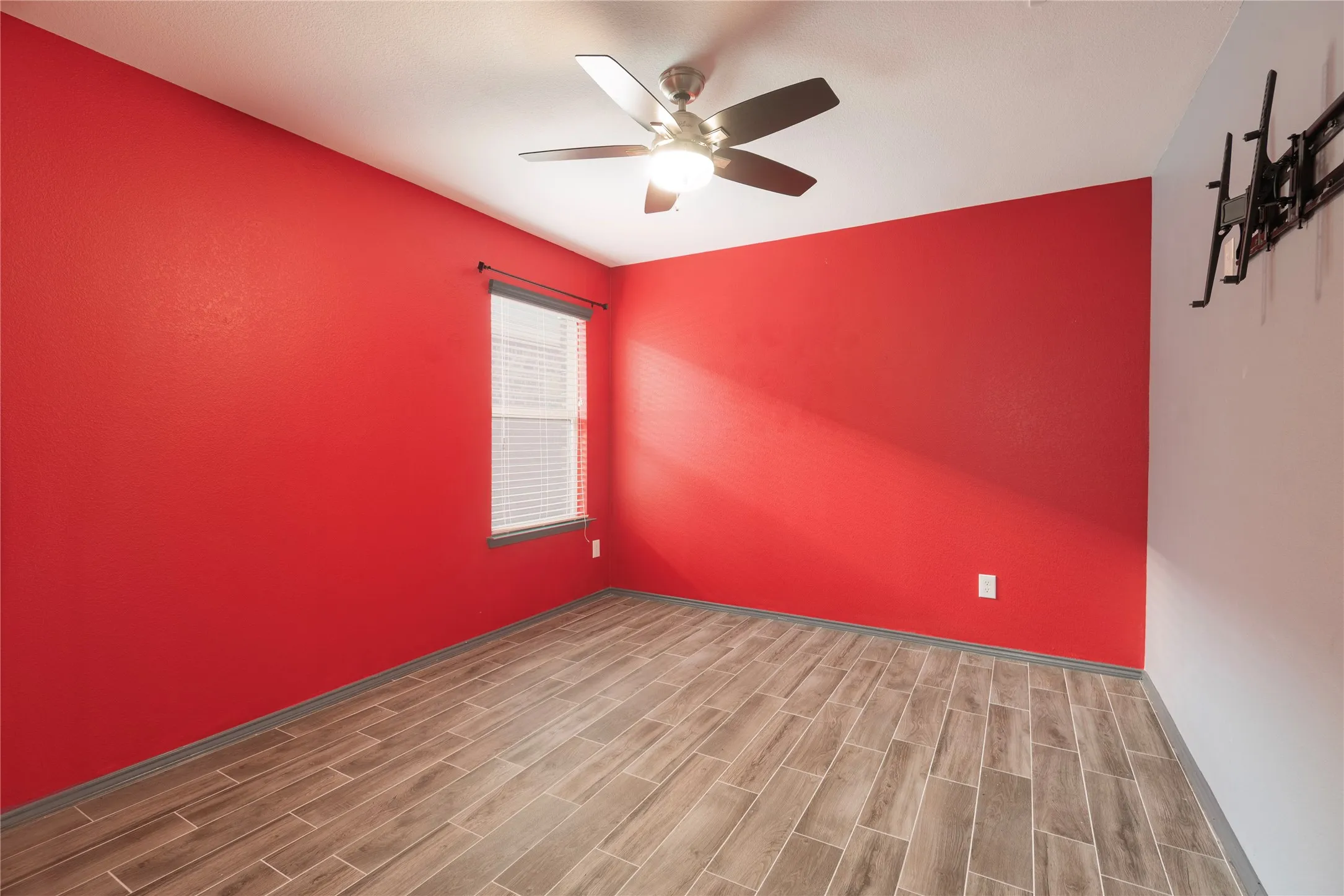 Room with wood-finish flooring, a ceiling fan, and a window with blinds