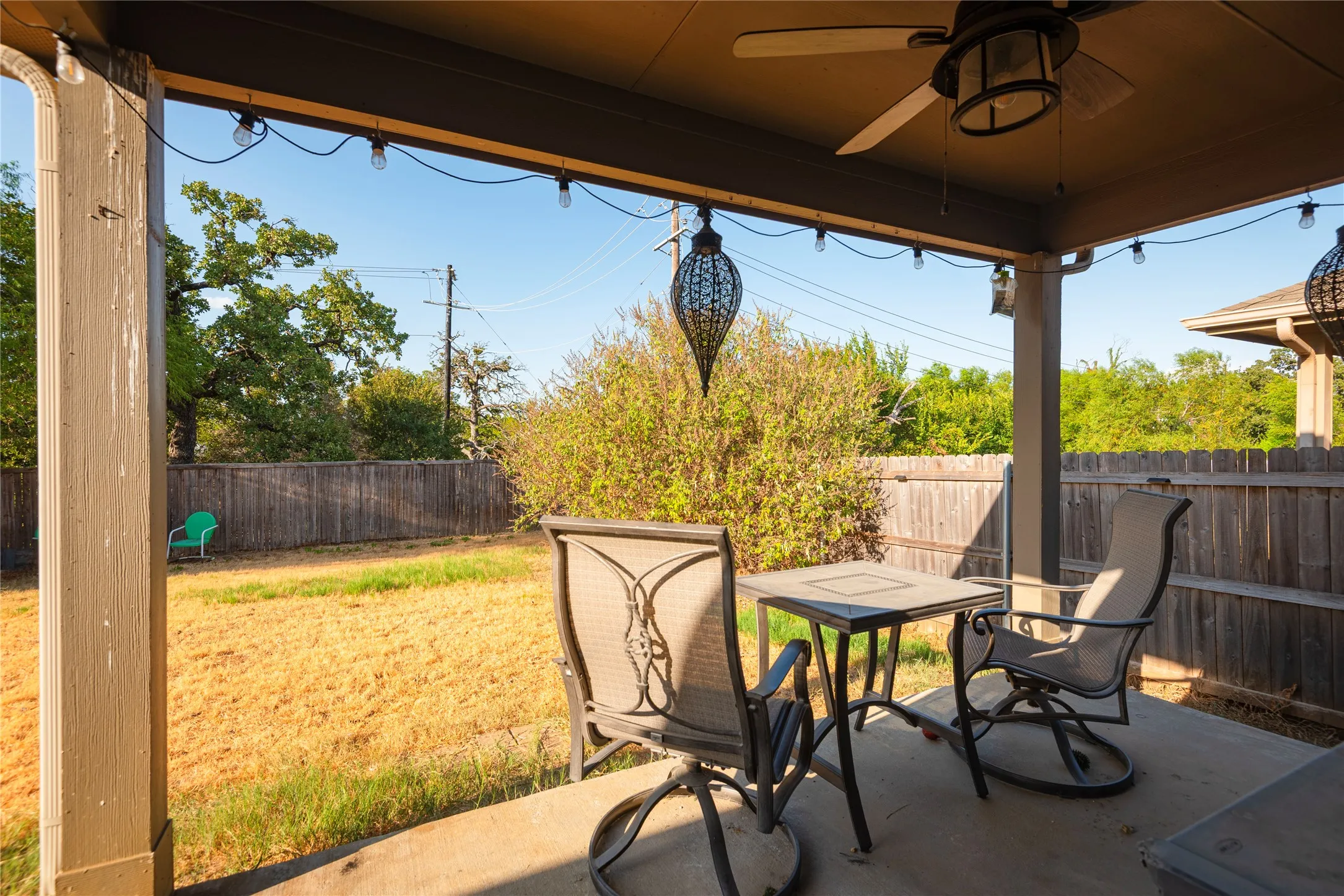 Covered patio with concrete flooring, overhead ceiling fan, and string lighting