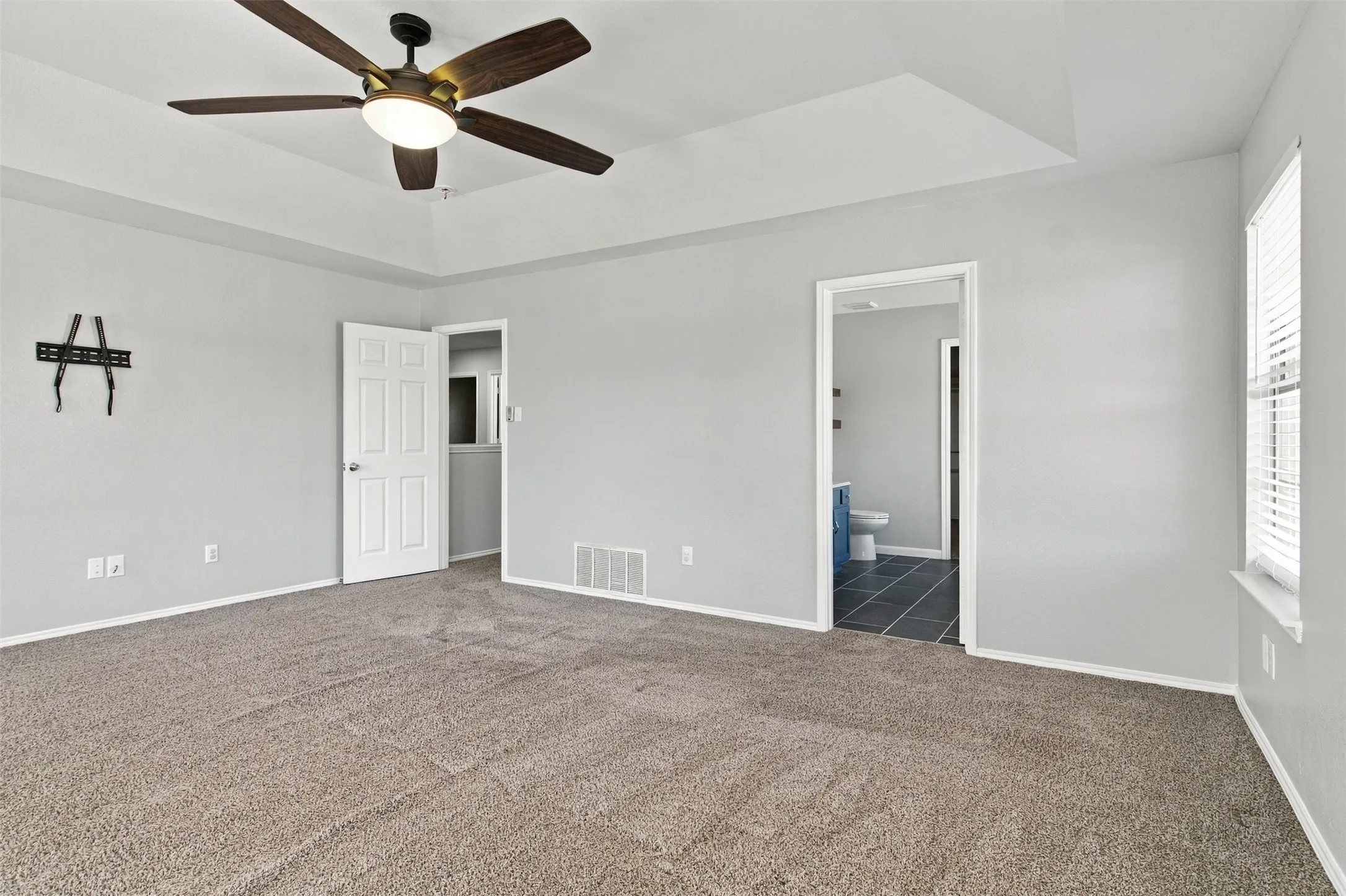 Tray ceiling with a ceiling fan, light gray wall paint, and plush carpet flooring