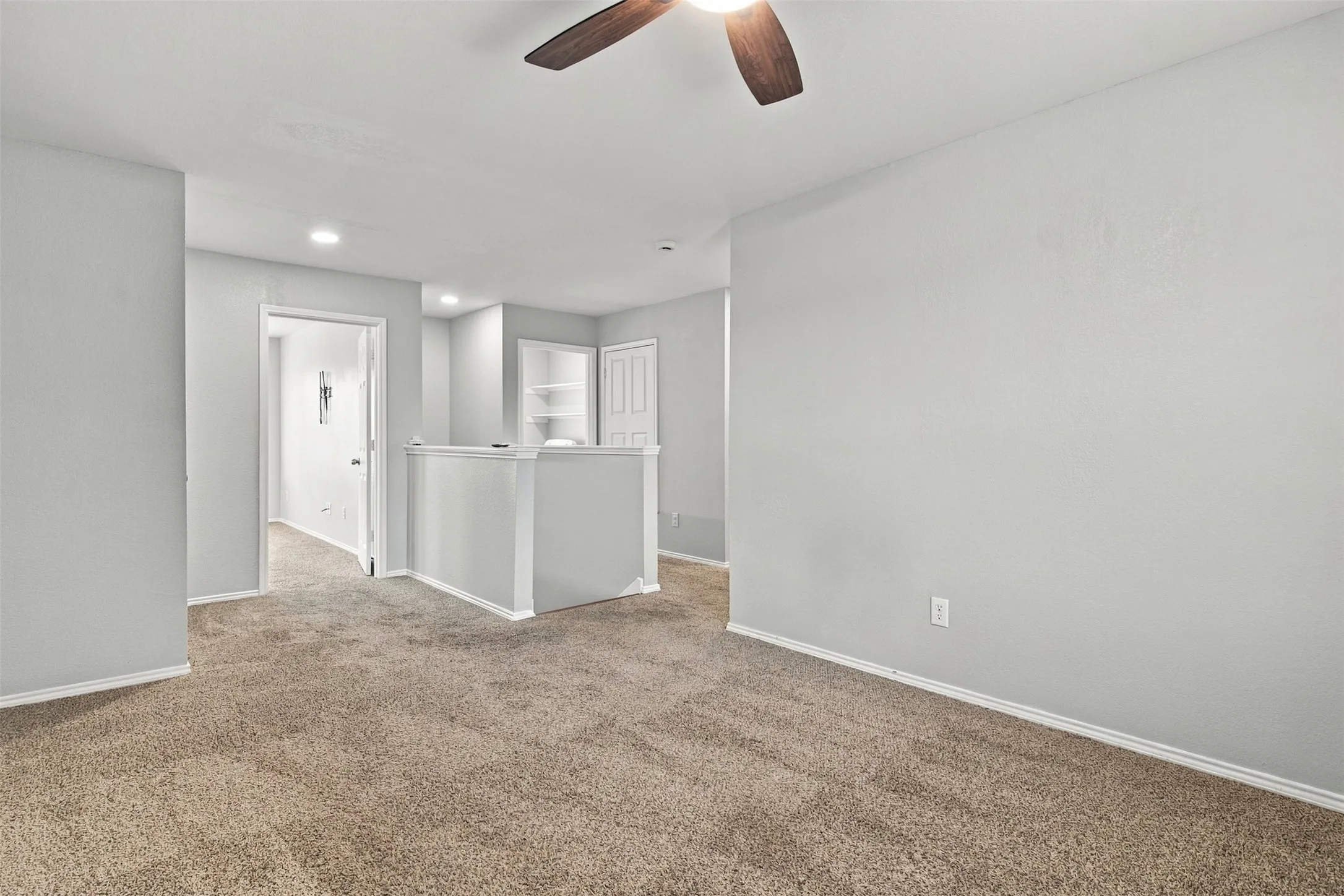 Carpeted flooring with light gray wall paint, recessed lighting, ceiling fan, and built-in shelving