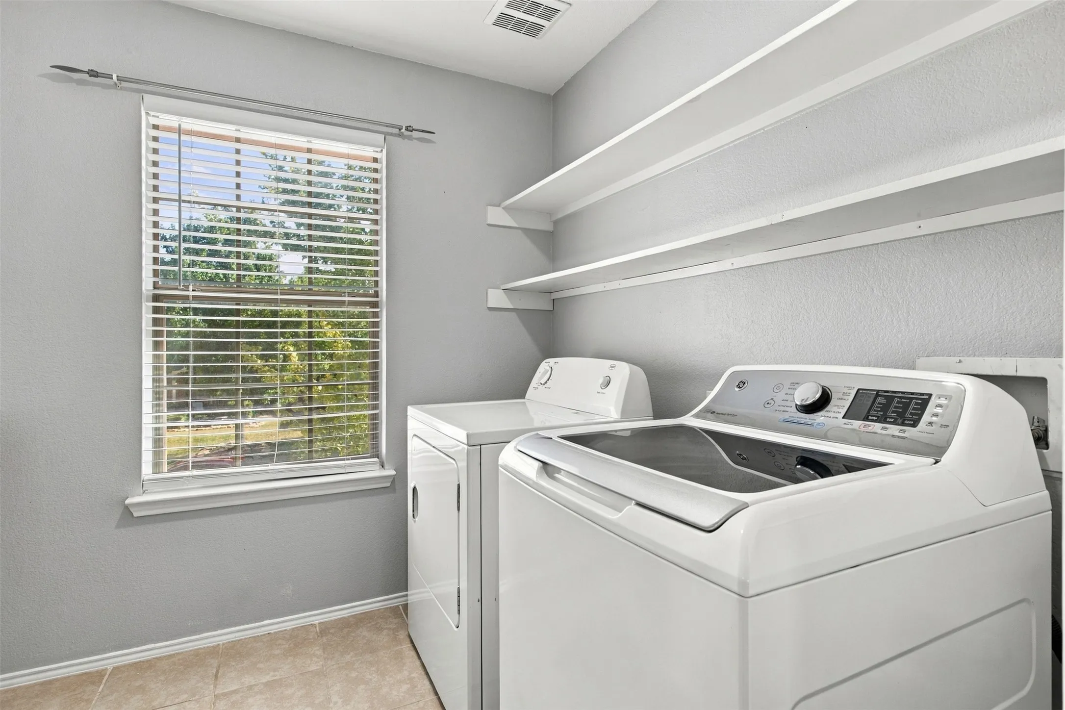 Laundry area featuring a window, built-in shelving, and tile flooring