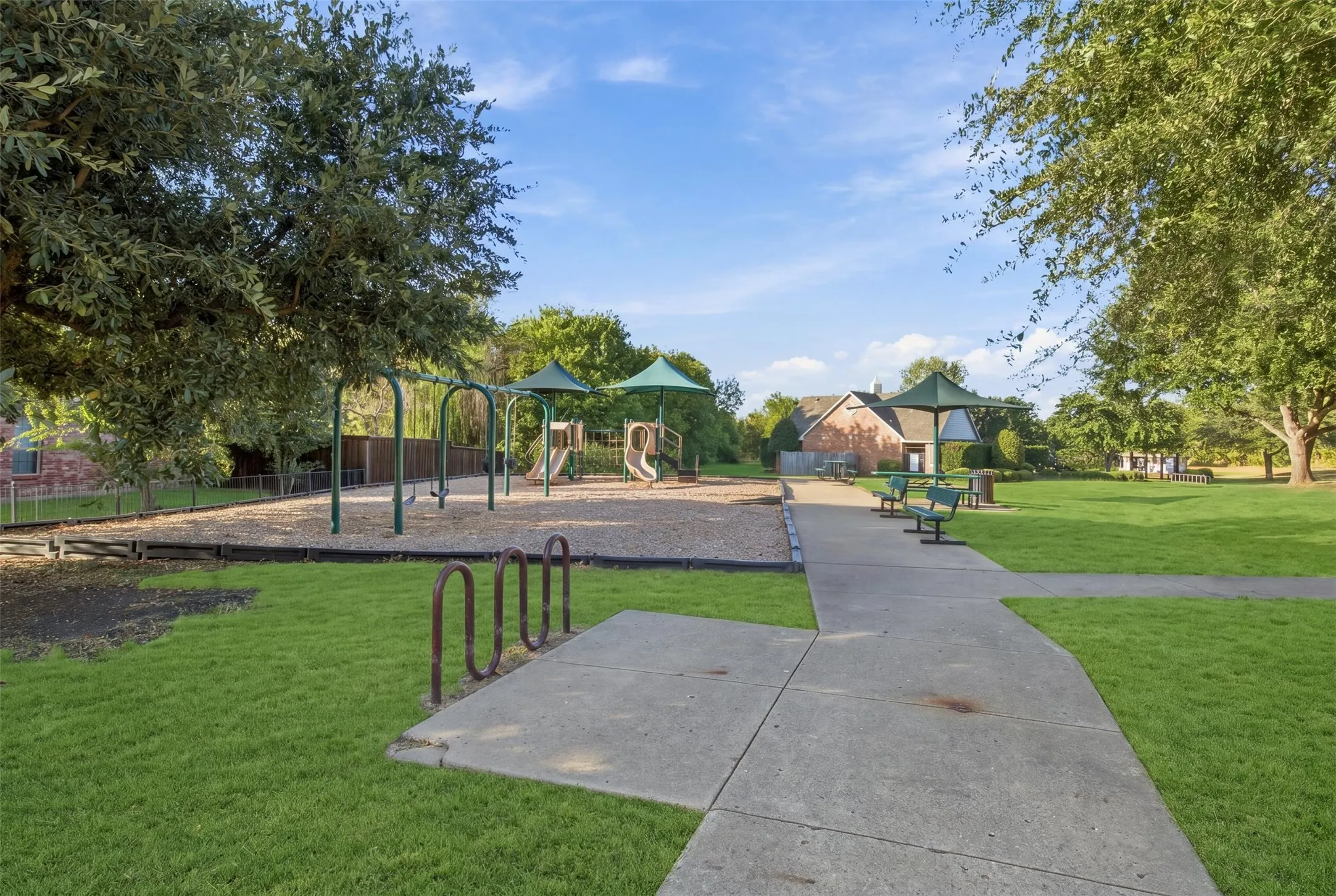 Community park featuring a playground, swing set, concrete pathways, and open green spaces