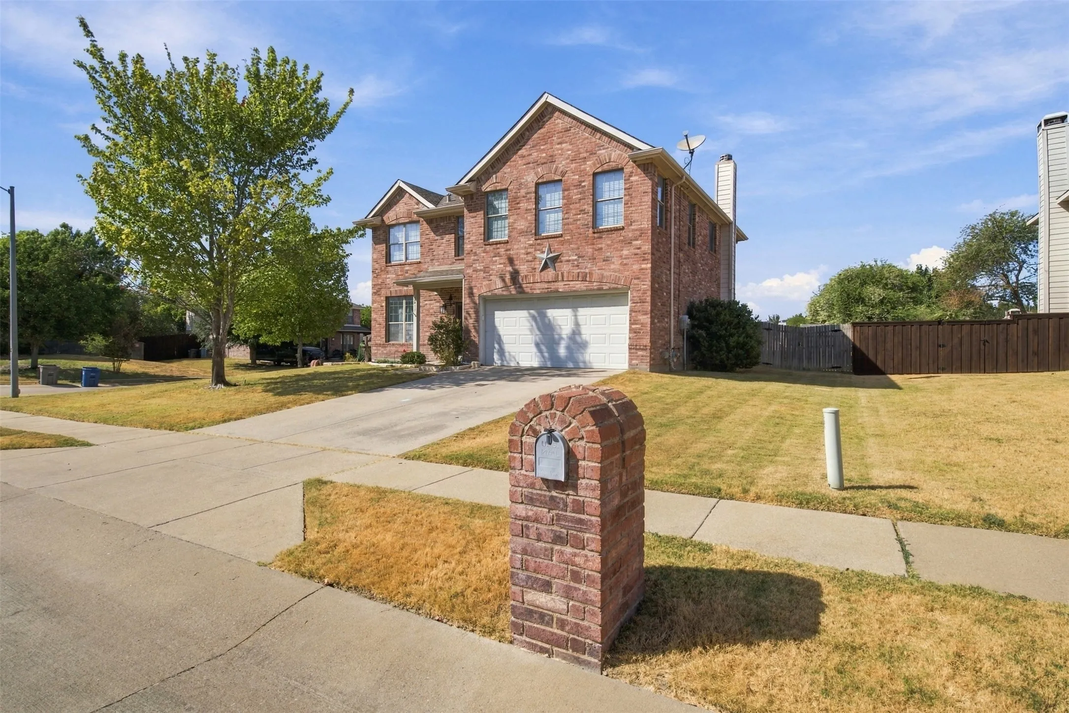 Brick exterior residence featuring multiple windows, an attached two-car garage, and a concrete driveway