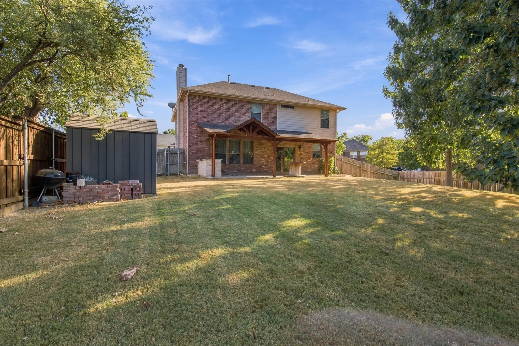 Expansive backyard with a manicured lawn, wood fencing, and mature trees
