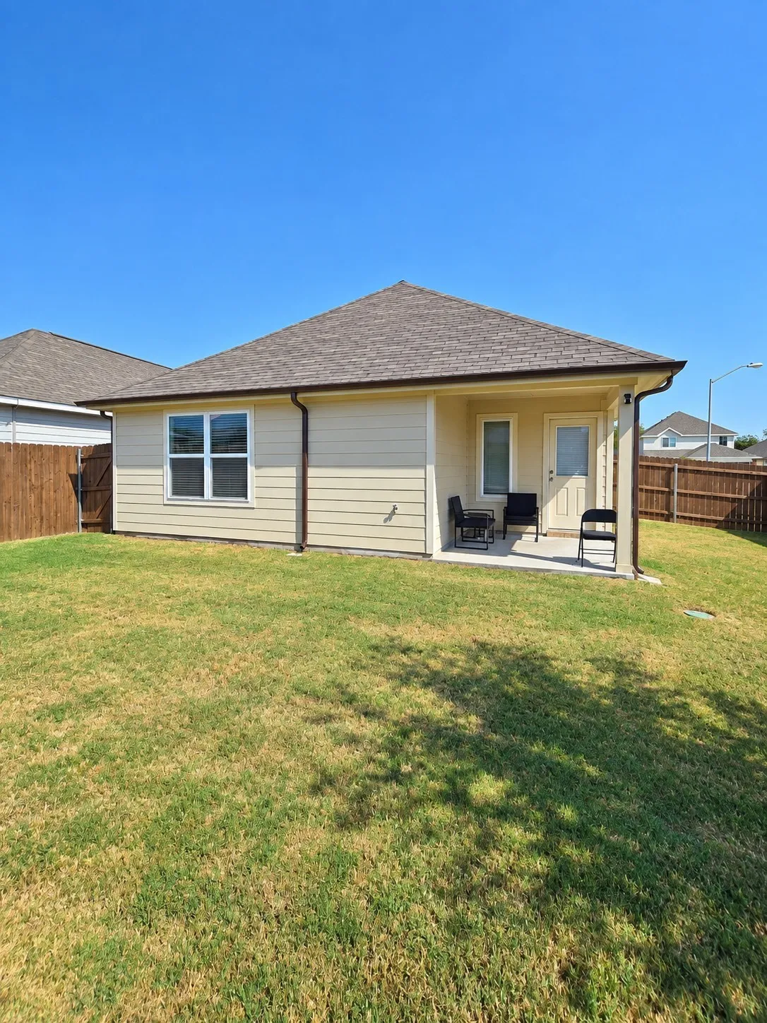 Rear exterior featuring a covered patio, a single-paned window, and a wooden fence