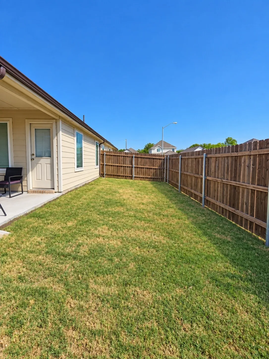 Private fenced backyard featuring a patio, wood privacy fencing, and a grass lawn