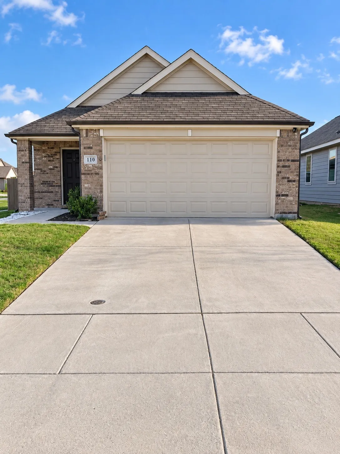 Brick veneer exterior with gabled roofline, attached garage, and concrete driveway